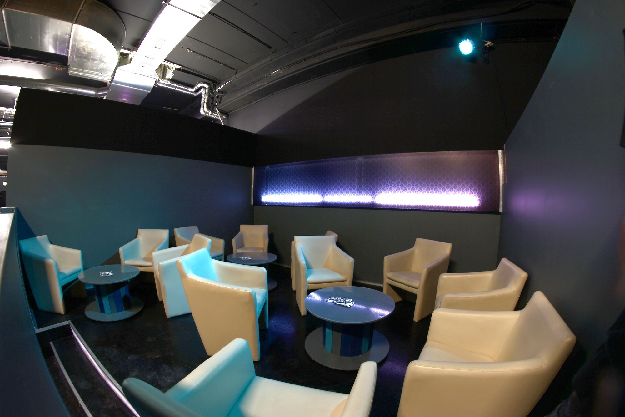 Bézs színű fotelekkel és kerek asztalokkal berendezett társalgó egy modern szobában.