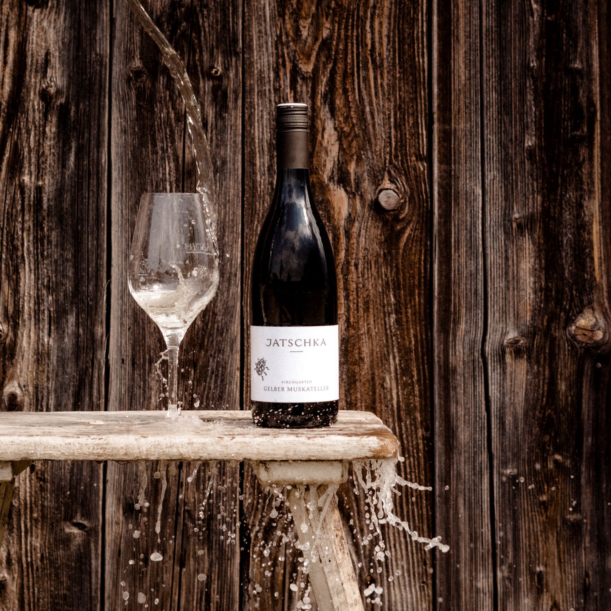 Borosüveg és pohár vízzel a fából készült fal előtt.