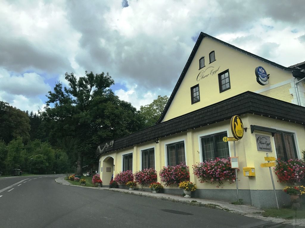 Gasthof Oberer Eggl virágokkal és buszmegállóval.