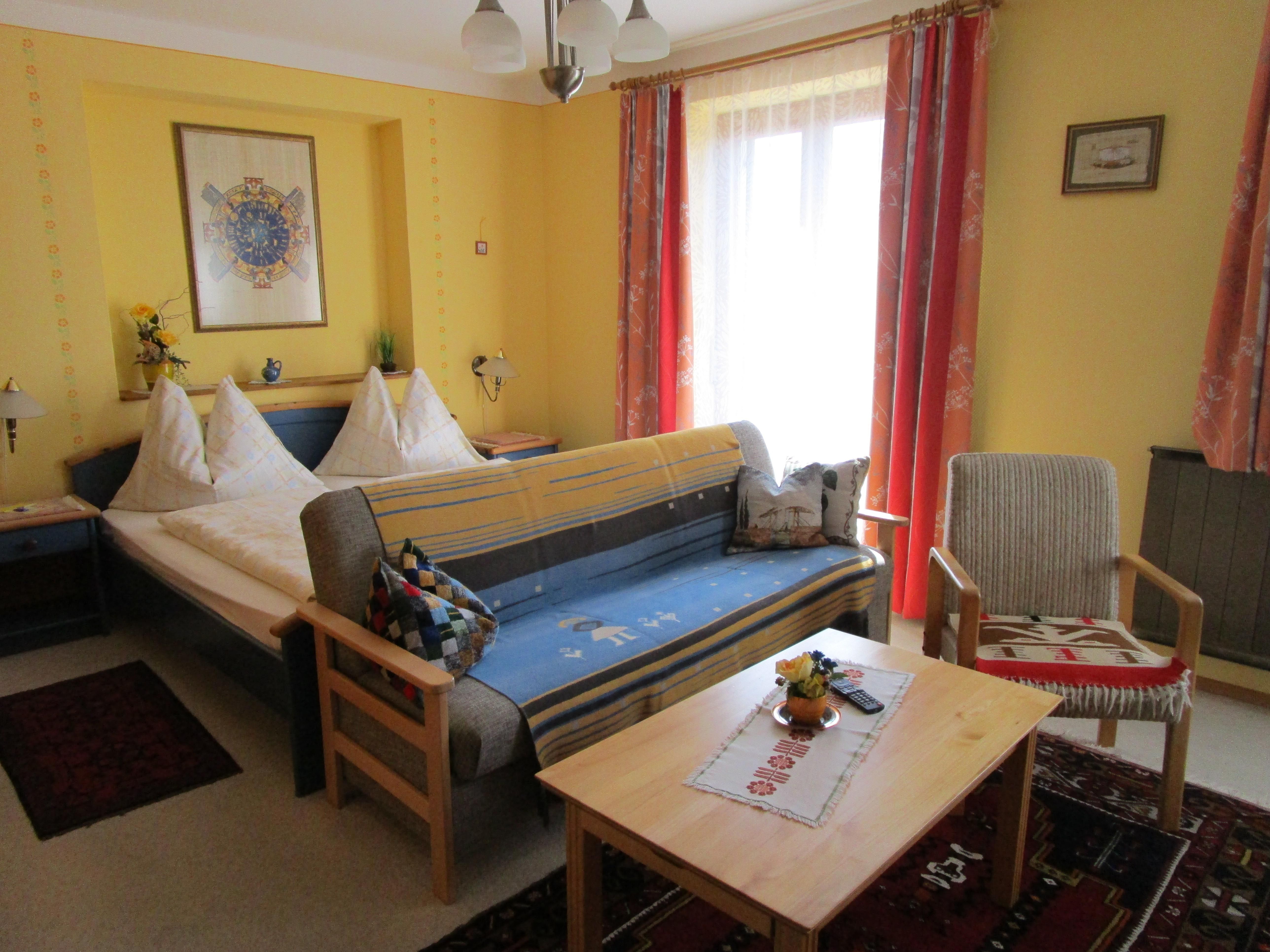 Szoba franciaággyal és kanapéval és asztallal az előtérben