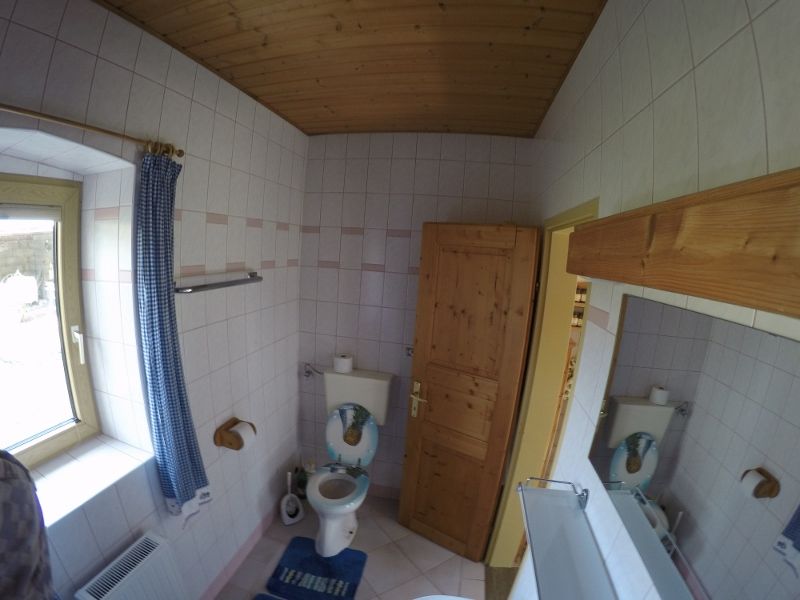 Fürdőszoba WC-vel, fa mennyezet és ablak kék függönnyel.
