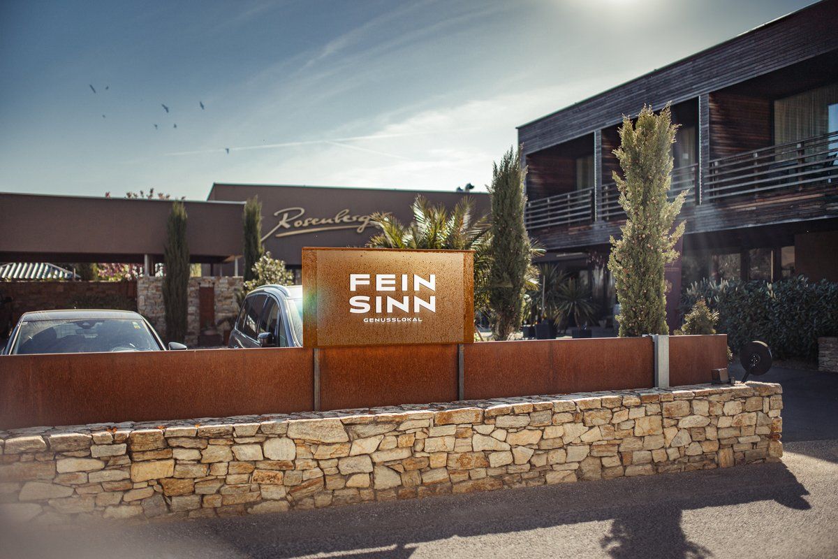 A Feinsinn Genusslokal bejárata modern építészeti és növényvilággal.