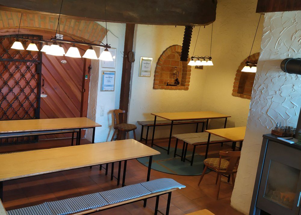 Hagyományos borozó belső nézete, fa asztalokkal, padokkal és rusztikus díszítéssel.