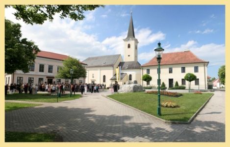 Absdorf plébániatemplom a környező térrel és a gyülekező emberekkel.