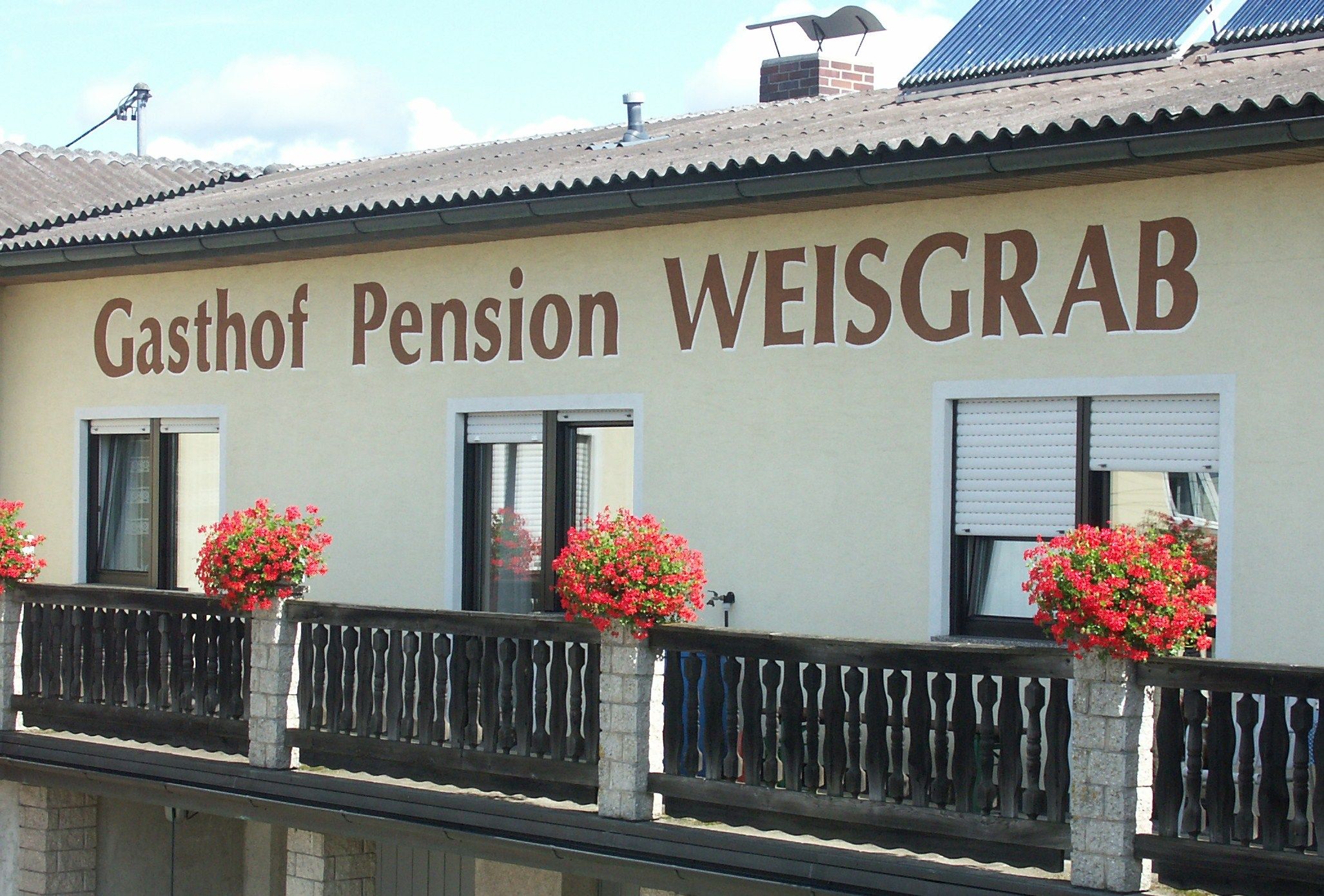 A Weisgrab panzió homlokzata, virágládákkal az erkélyen.
