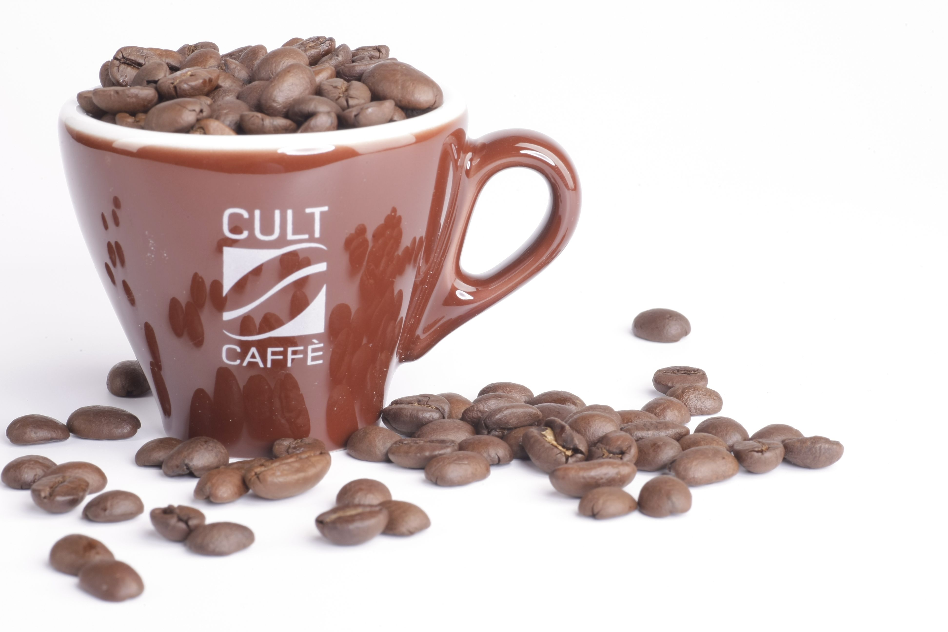 Barna bögre "Cult Caffè" felirattal, kávébabokkal töltve, fehér alapon.
