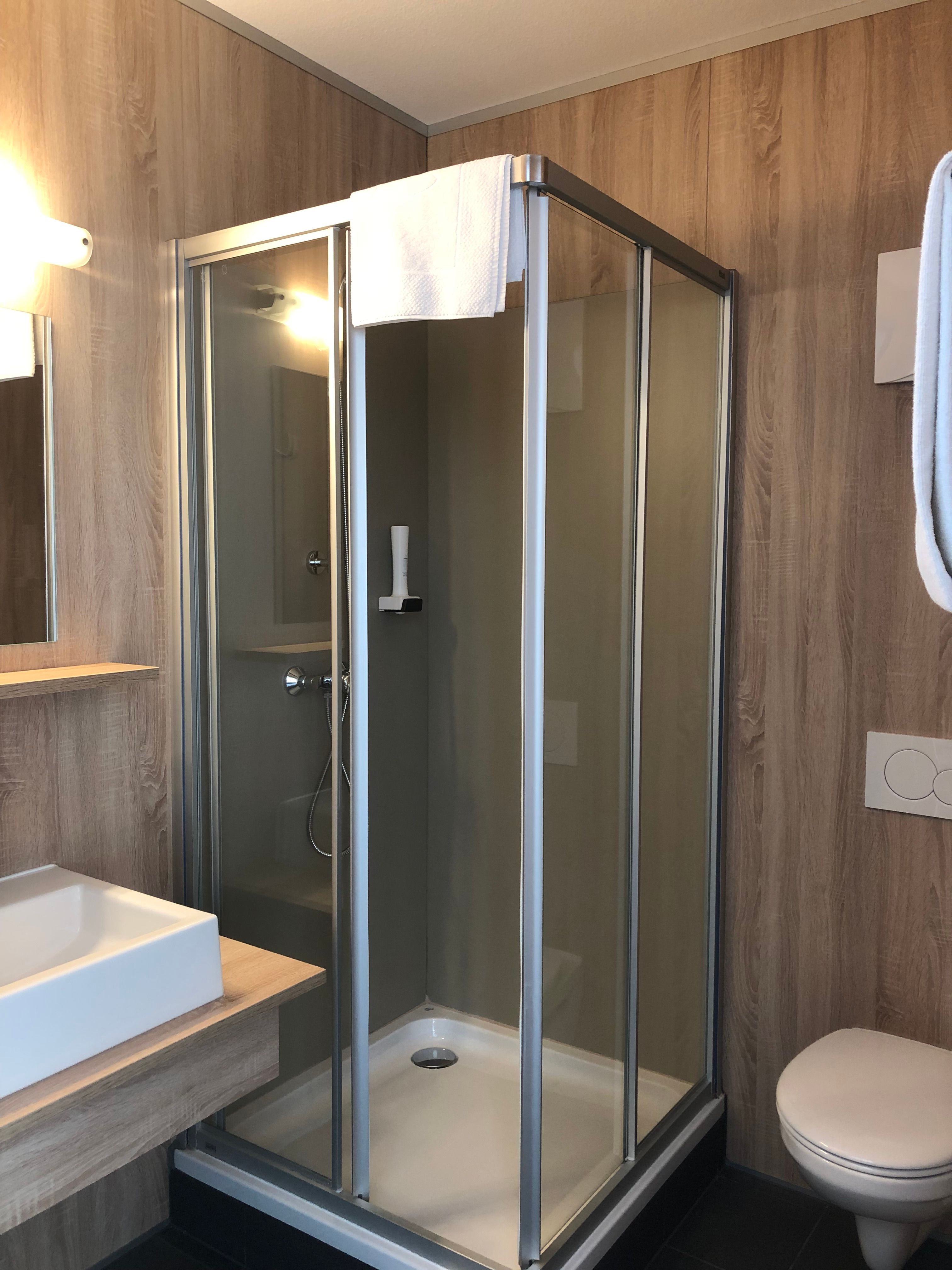 Modern fürdőszoba zuhanyzóval, mosdóval és WC-vel.