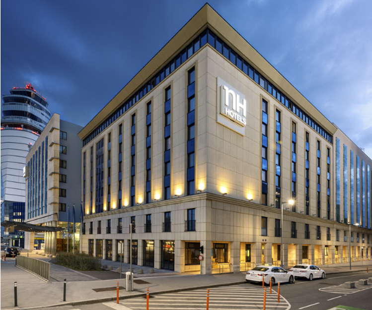 Az NH Vienna Airport konferenciaközpontja szürkületben, kivilágított épülettel.