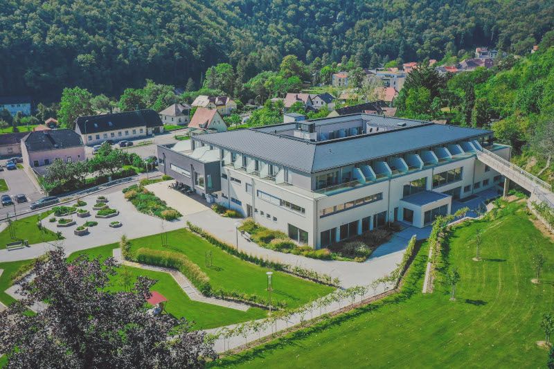 Légi felvétel egy modern épületről a kerttel és a környező tájjal.