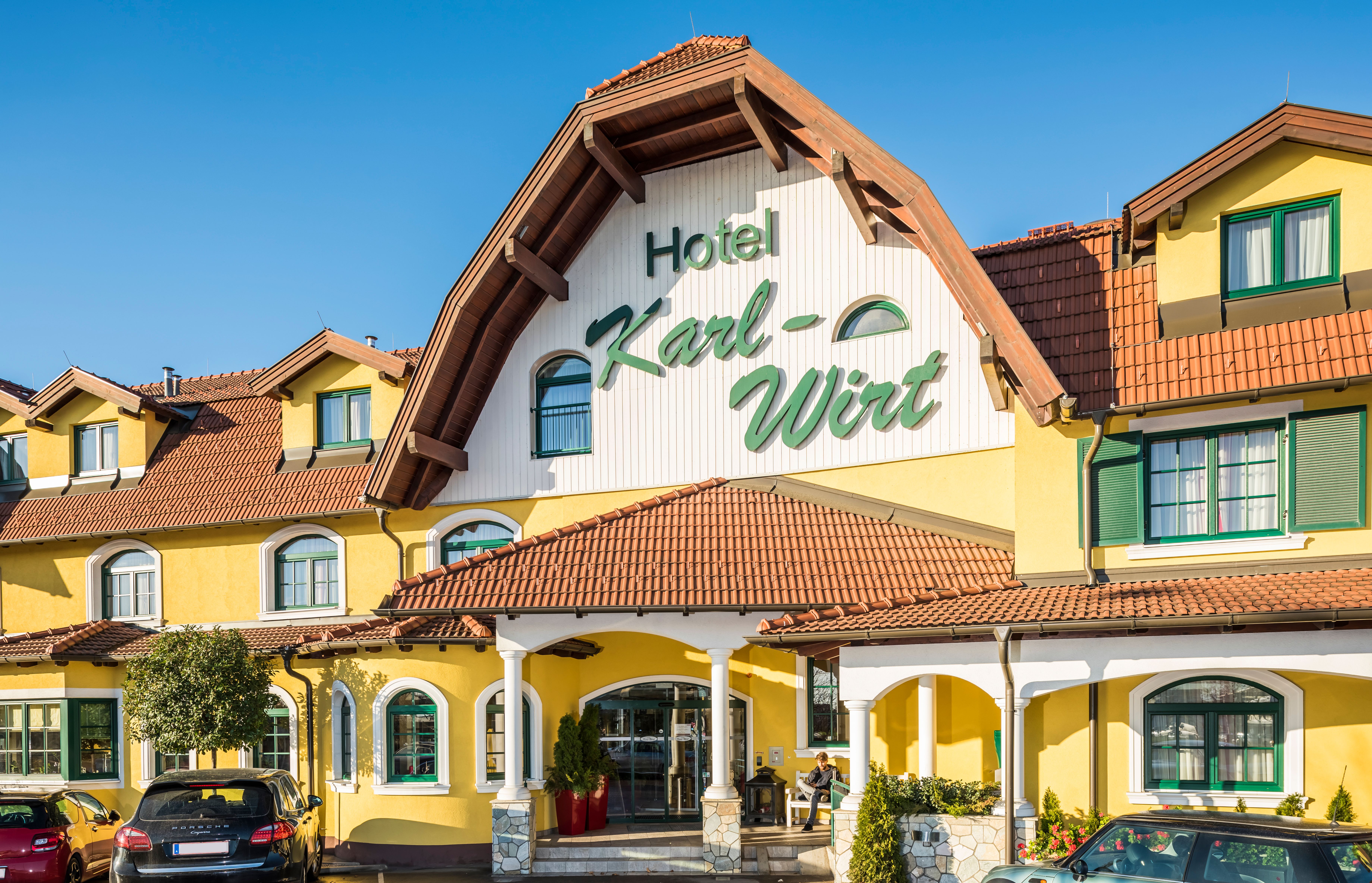 Sárga színű szállodaépület, a nyeregtetőn a "Hotel Karl-Wirt" felirattal.
