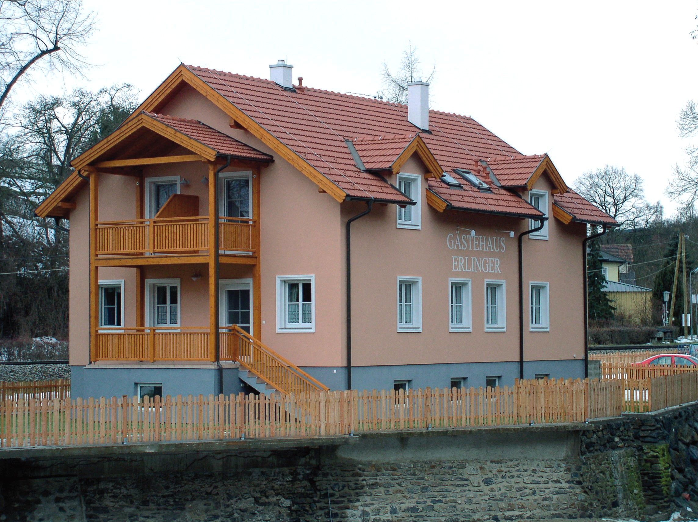 Erlinger vendégház fából készült verandával és kerítéssel.