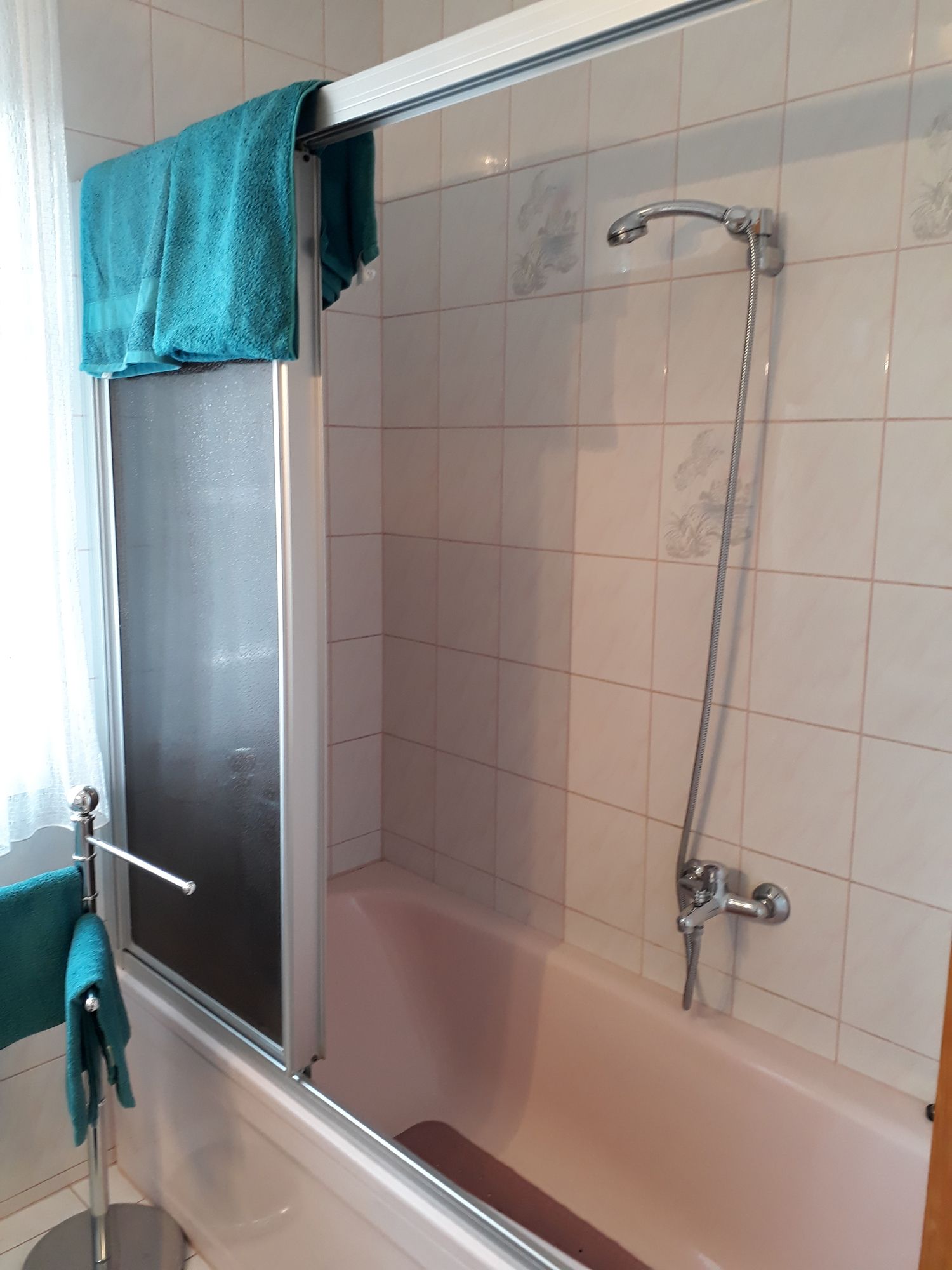 Fürdőszoba káddal, zuhanyfüggönnyel és kék törölközőkkel.