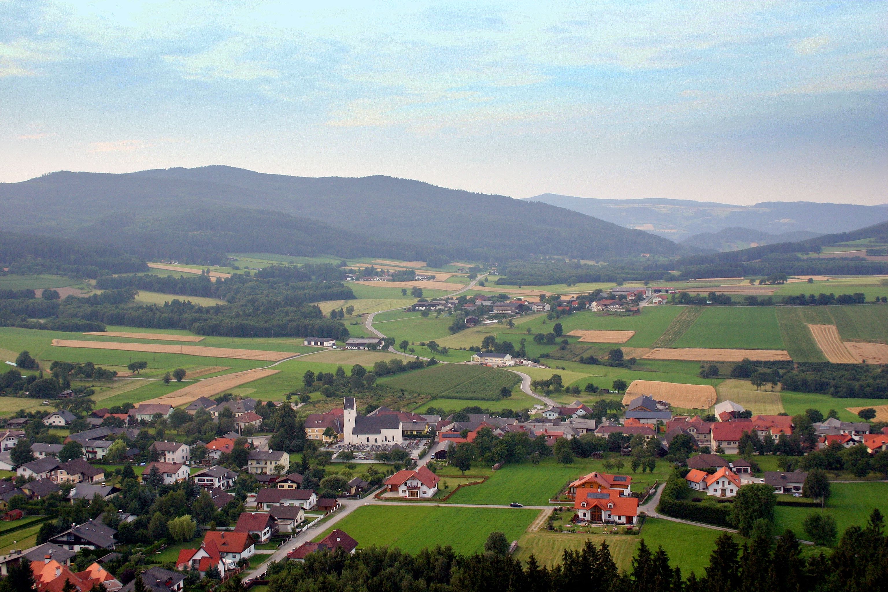 Münichreith am Ostrong tájképe, a háttérben mezők, házak és dombok.