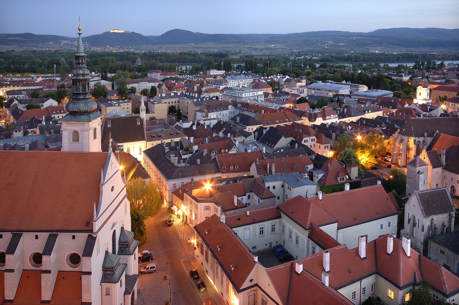 Krems esti látképe kivilágított épületekkel és dombokkal a háttérben.