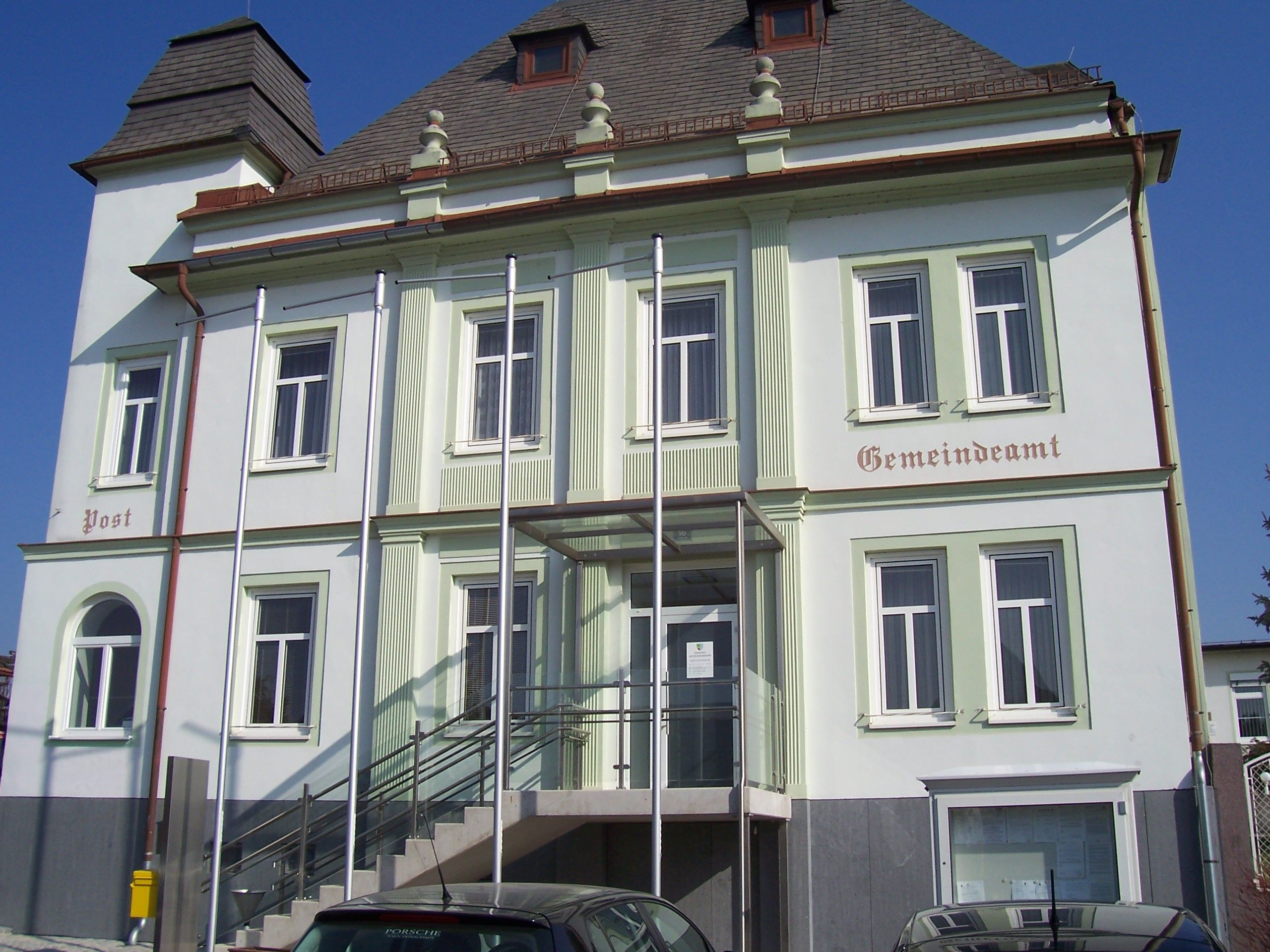 Untersiebenbrunn önkormányzati hivatal lépcsőkkel és zászlórudakkal az épület előtt.
