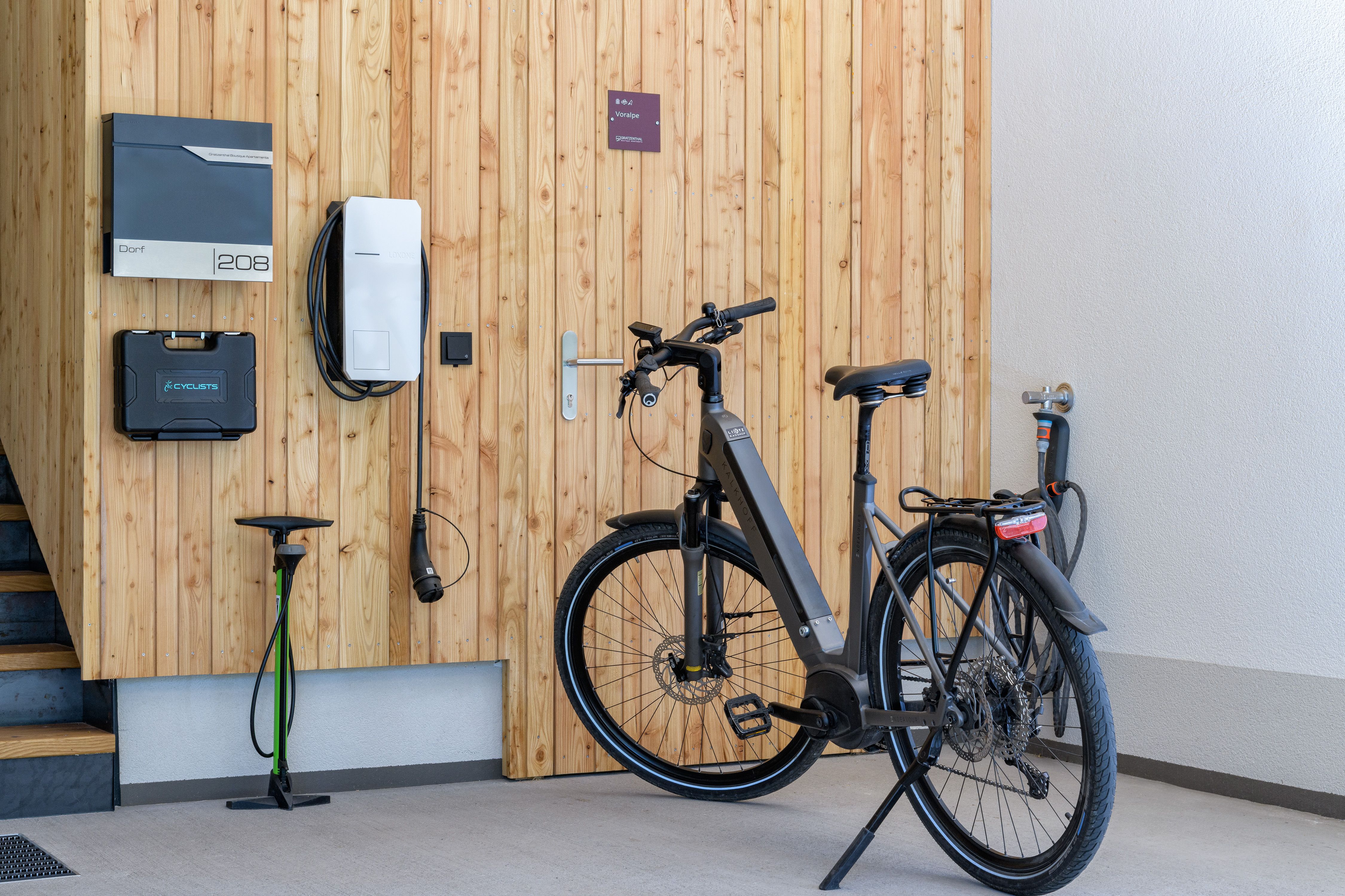 Egy modern e-kerékpár áll a garázsban egy fa fal melletti elektromos töltőállomás mellett.