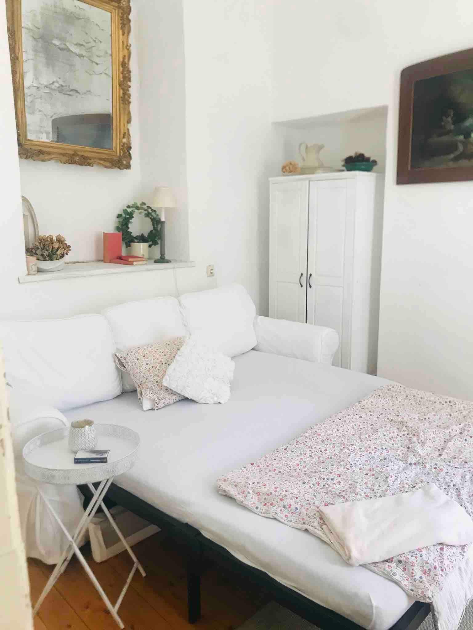 Hangulatos hálórész fehér kanapéval, asztalka és dekorációs elemek.