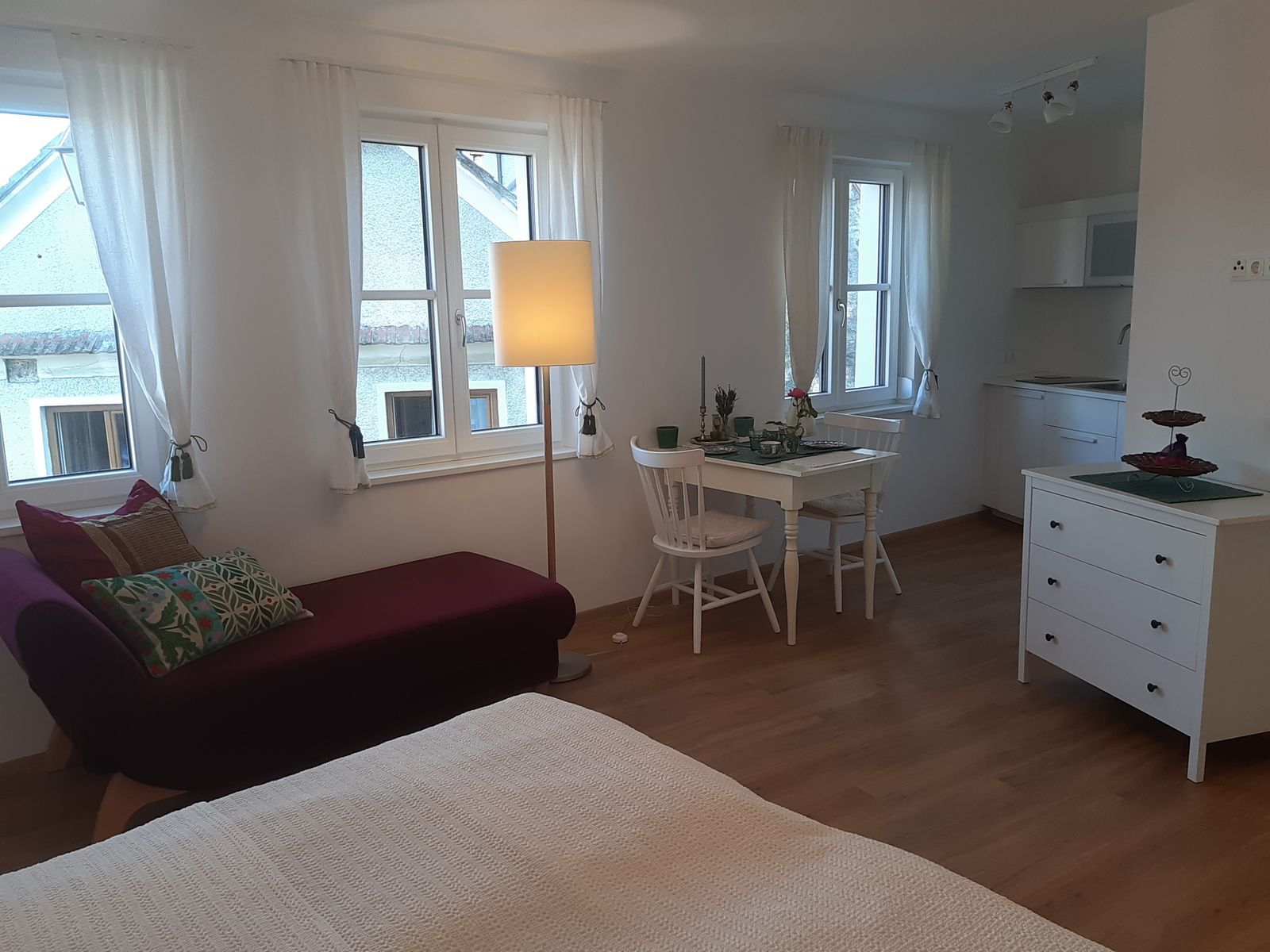 Világos lakás kanapéval, étkezőasztallal és konyhasarokkal.