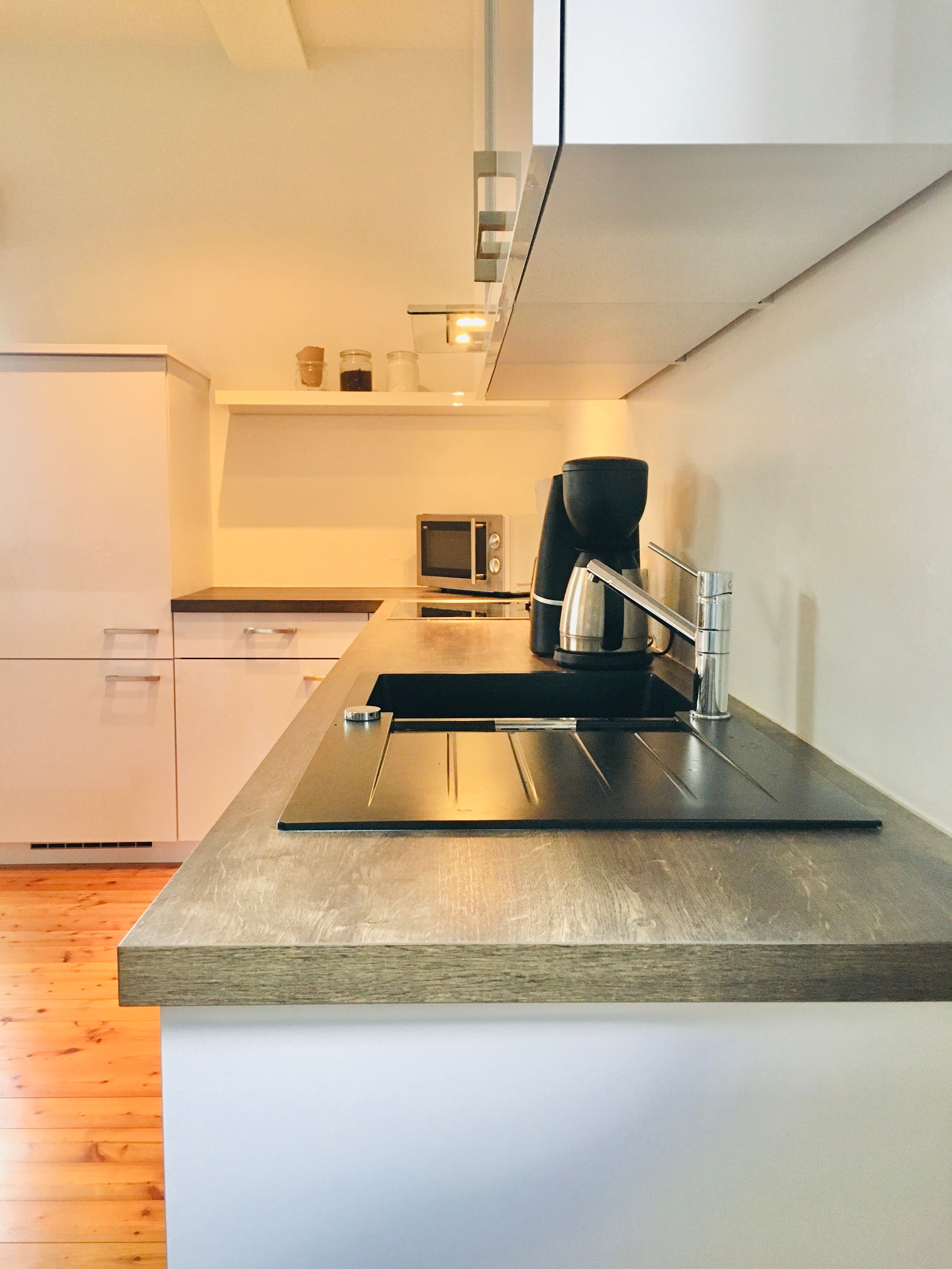 Modern konyha fa munkalapokkal, mosogatóval, kávéfőzővel és mikrohullámú sütővel.