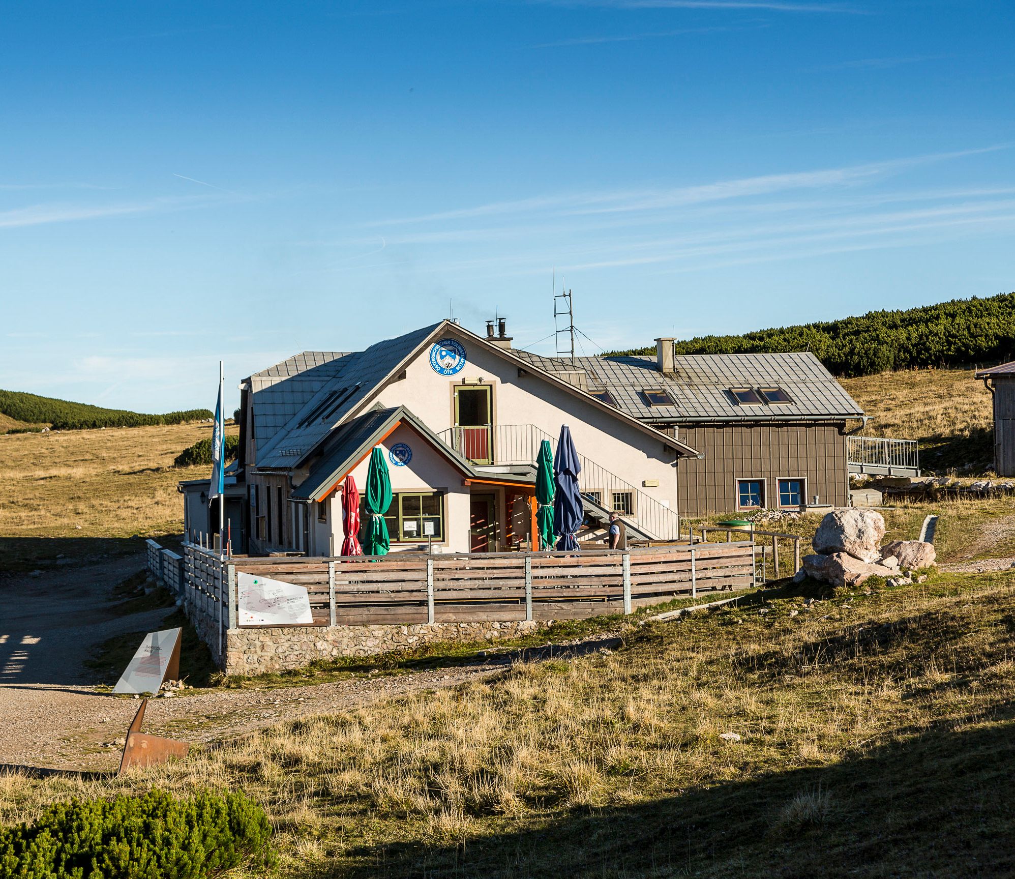A Damböckhaus a Schneeberg-hegyen, napsütötte hegyvidéki tájban, kék égbolt mellett.