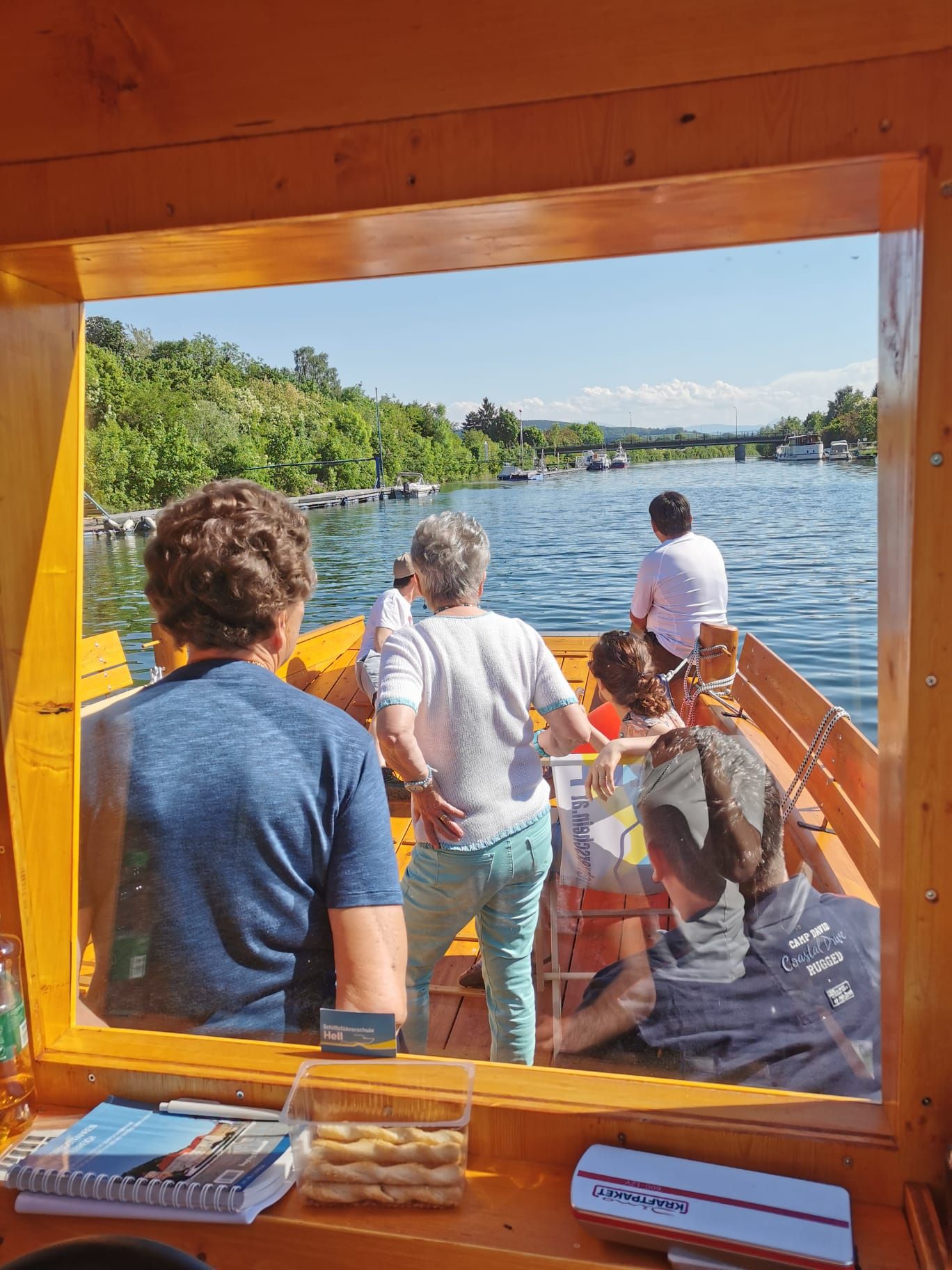 Kilátás egy folyami csónakból, több emberrel a fedélzeten.