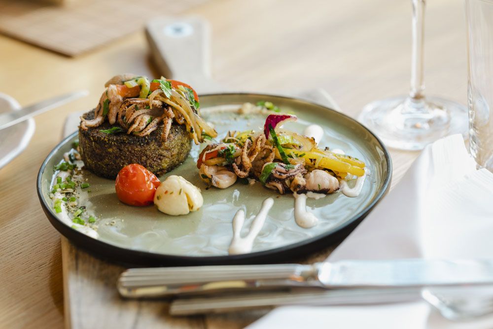 Ínyenc étel tányéron zöldségekkel és tenger gyümölcseivel, dekoratívan elrendezve.