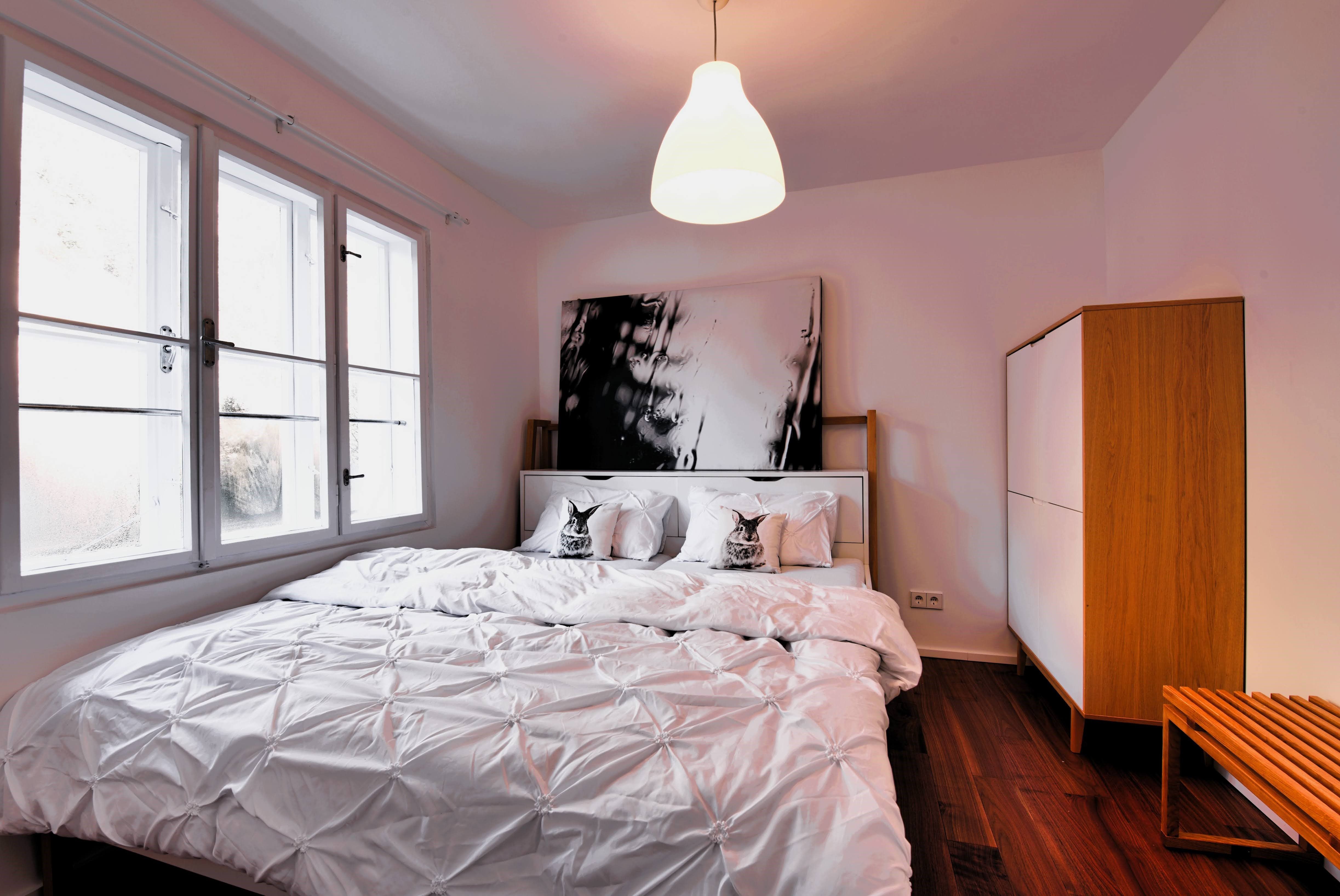 Modern hálószoba nagy ággyal, fehér ágyneművel és fa szekrénnyel.