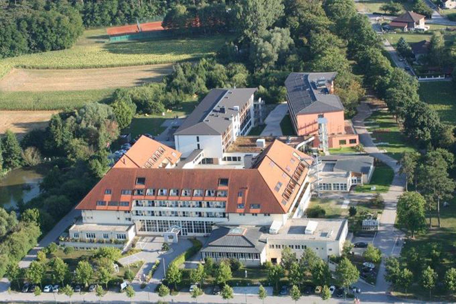 Légi felvétel egy piros tetős klinikáról, amelyet fák és mezők vesznek körül.