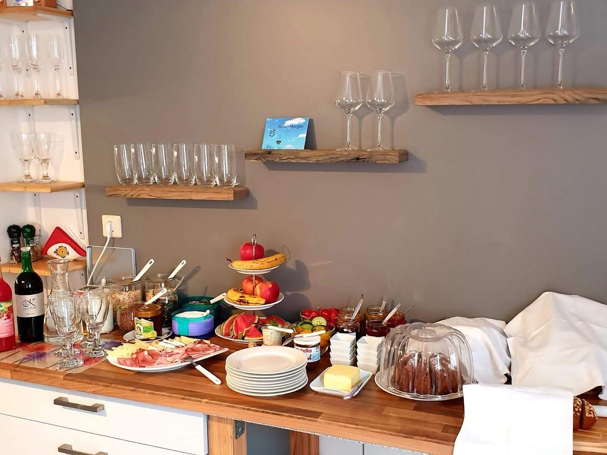 Svédasztalos reggeli poharakkal, gyümölcsökkel, felvágottakkal és süteményekkel.