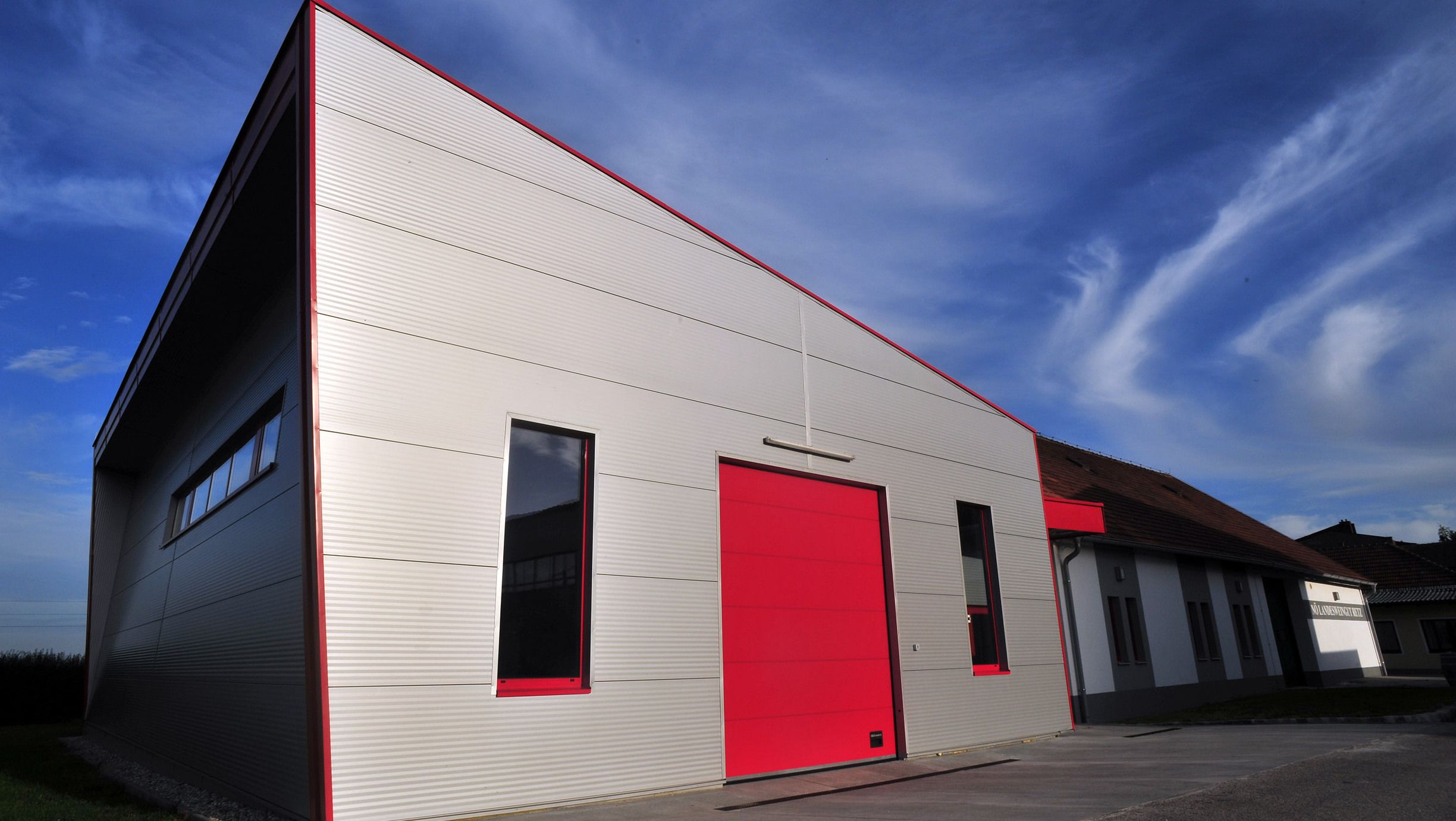 Modern épület piros kapuval és kék éggel a háttérben.