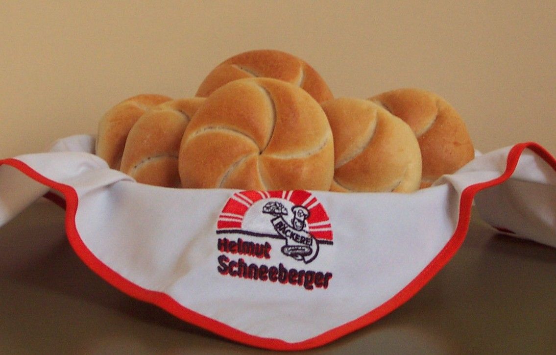 Egy kosár friss zsemle, szalvétával letakarva a Helmut Schneeberger pékségből.