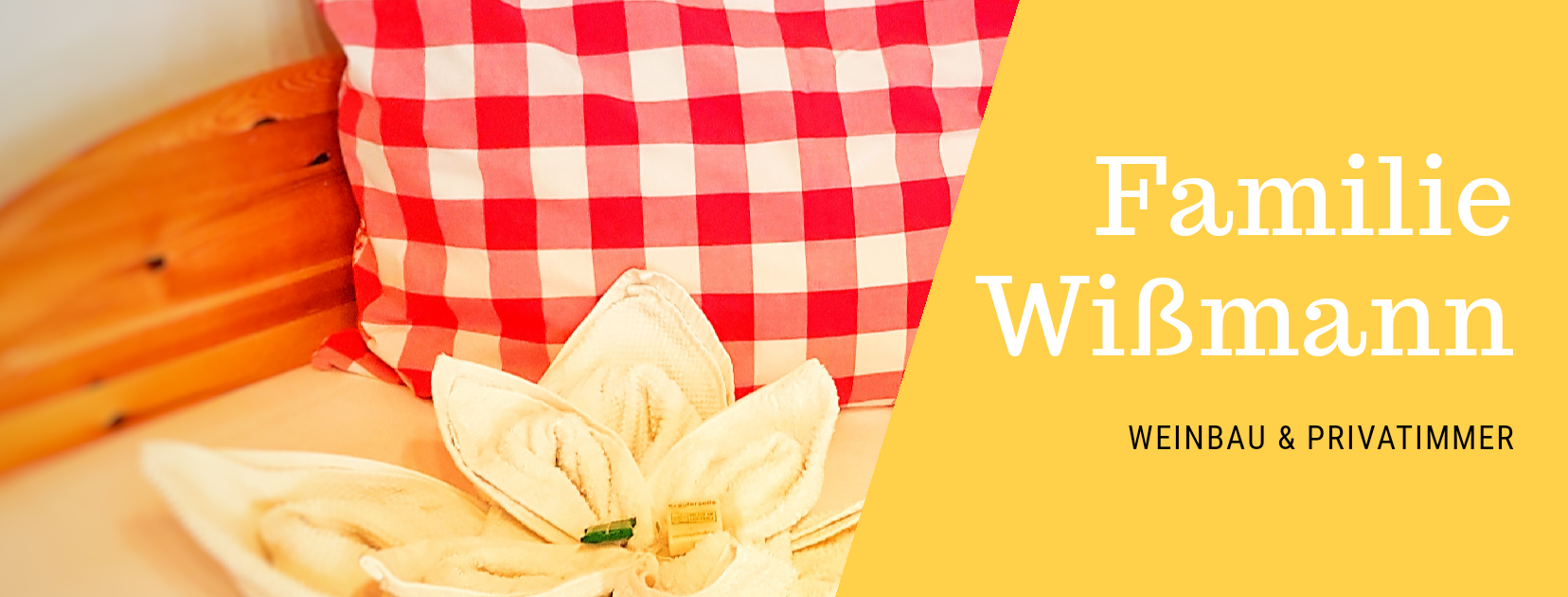 Piros, kockás mintás párna és virág alakú törölköző egy ágyon. Szöveg: Wißmann család, borászat és magánszobák.