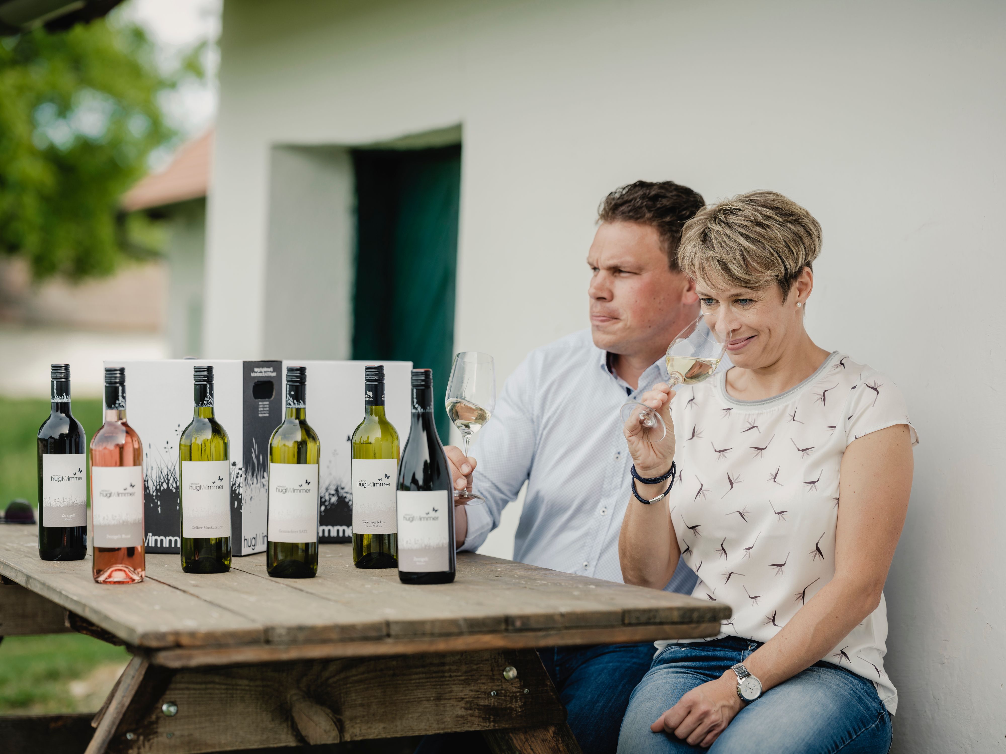 Két ember ül egy asztalnál borosüvegekkel és borkóstolóval.