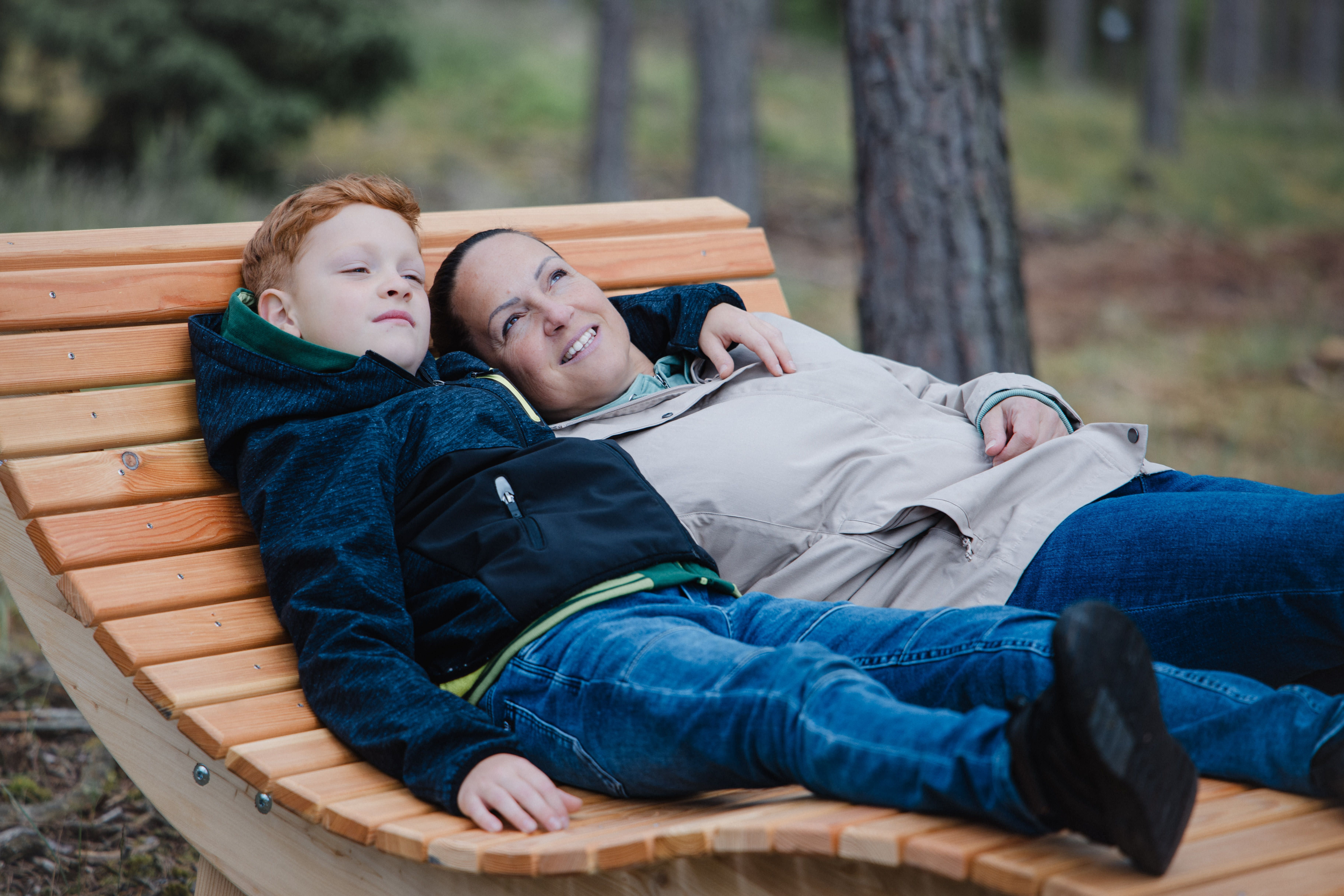 Két ember pihen egy fapadon az erdőben.