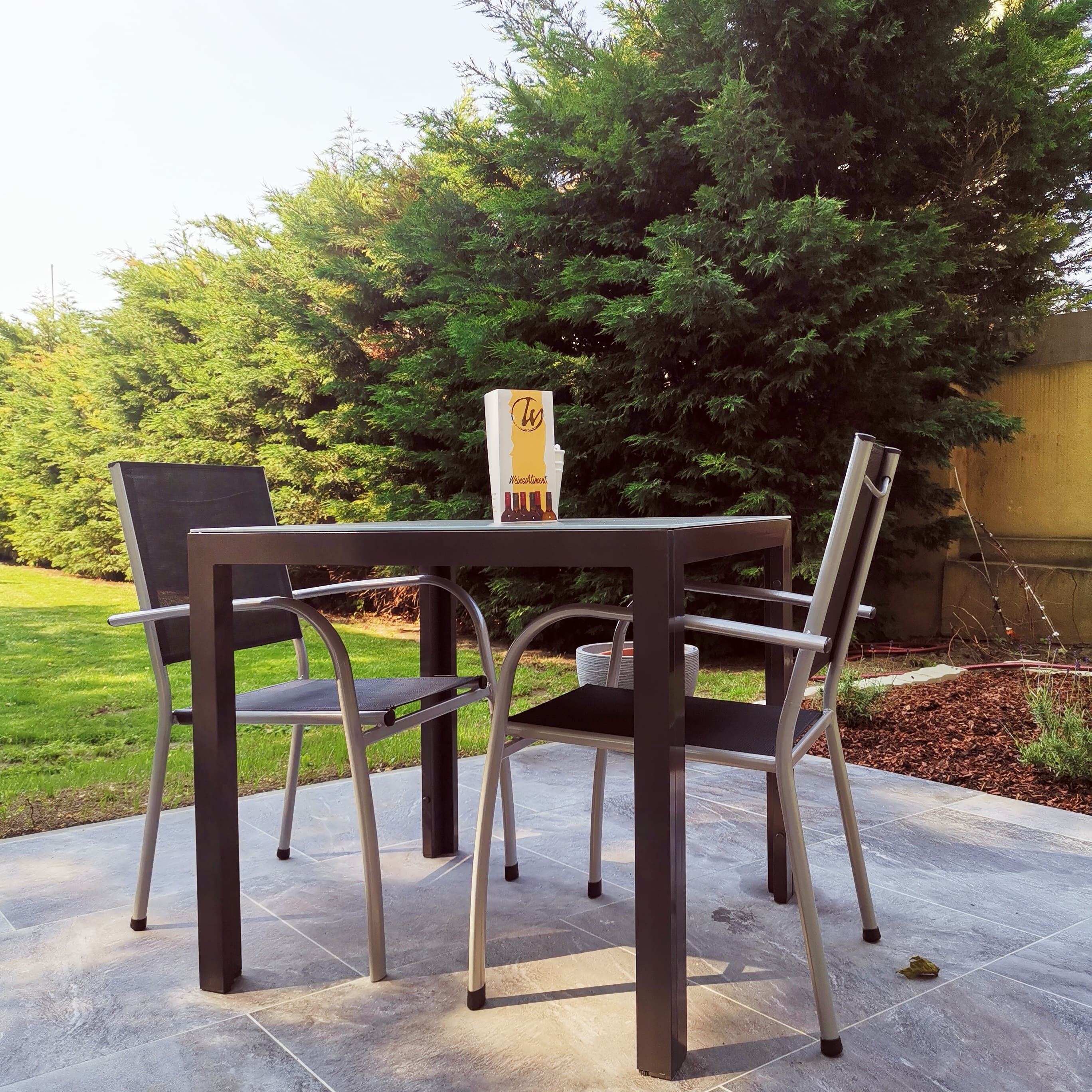 Terasz asztallal, két székkel és fákkal a háttérben.