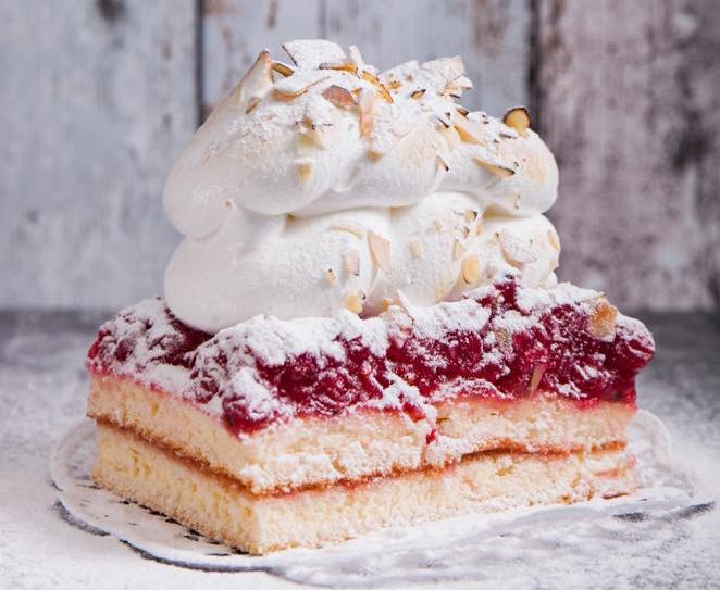 Egy szelet torta tejszínhabbal és darált mandulával körítve.