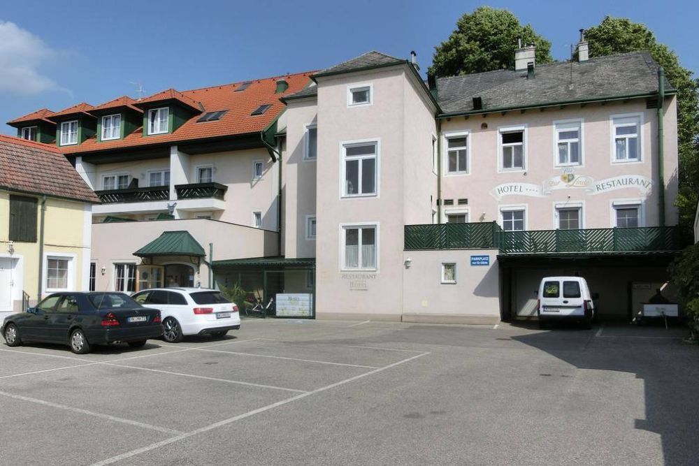 Egy szálloda külső nézete parkolóval és autókkal.