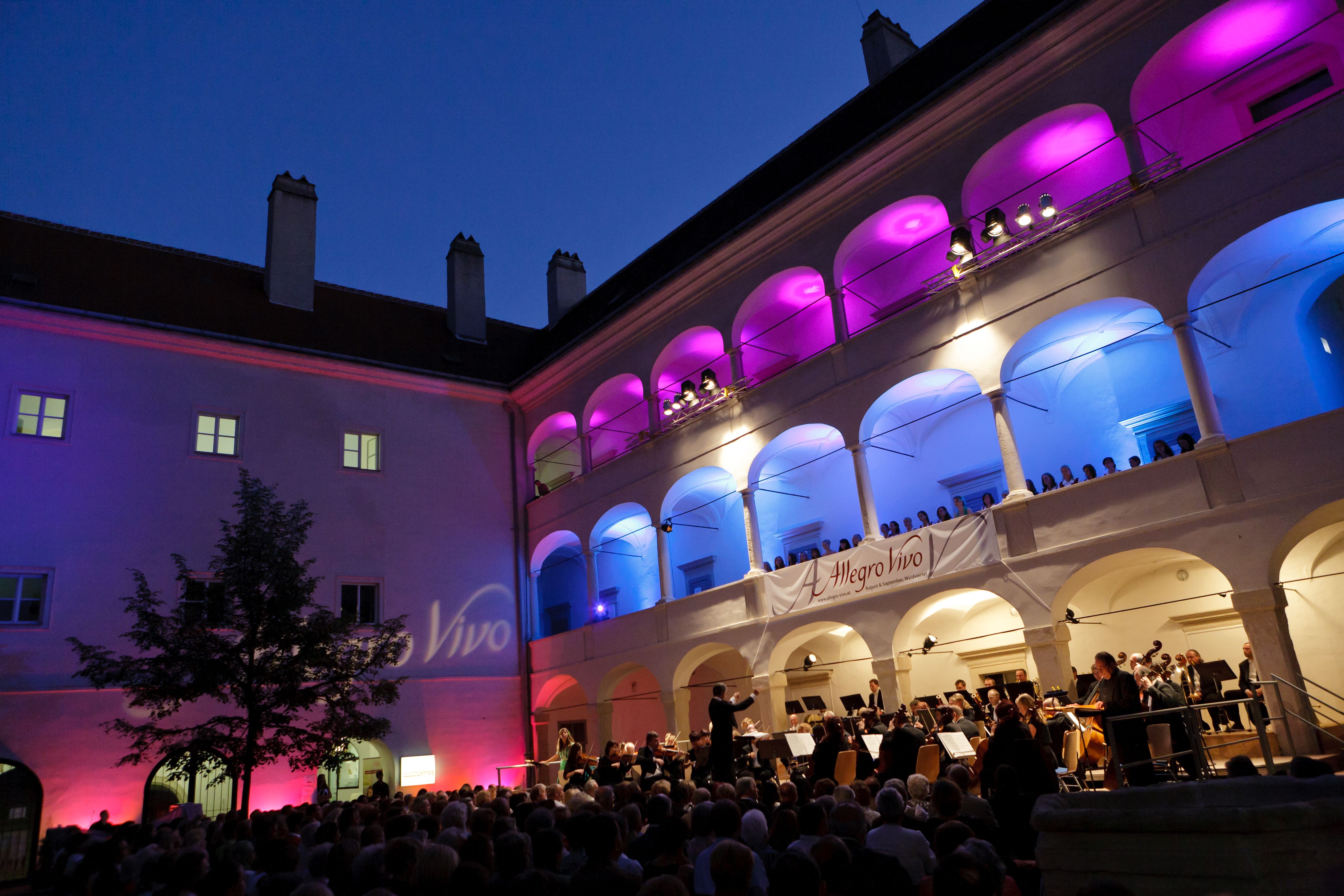 Koncert a Kunsthaus Horn árkádos udvarán éjszaka, színes világítással.