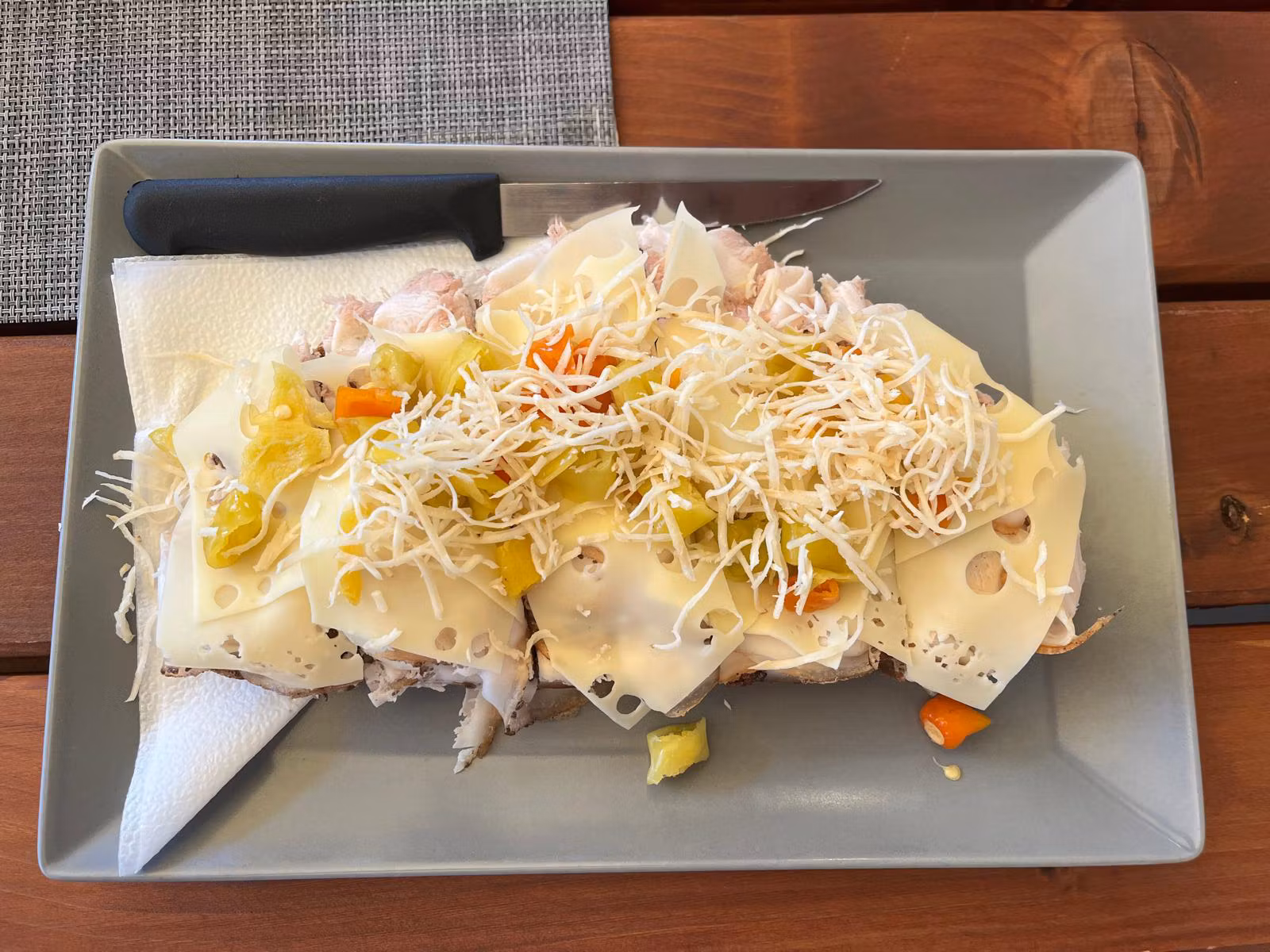 Sajtos szendvics zöldségekkel és reszelt tormával, szürke tányéron.