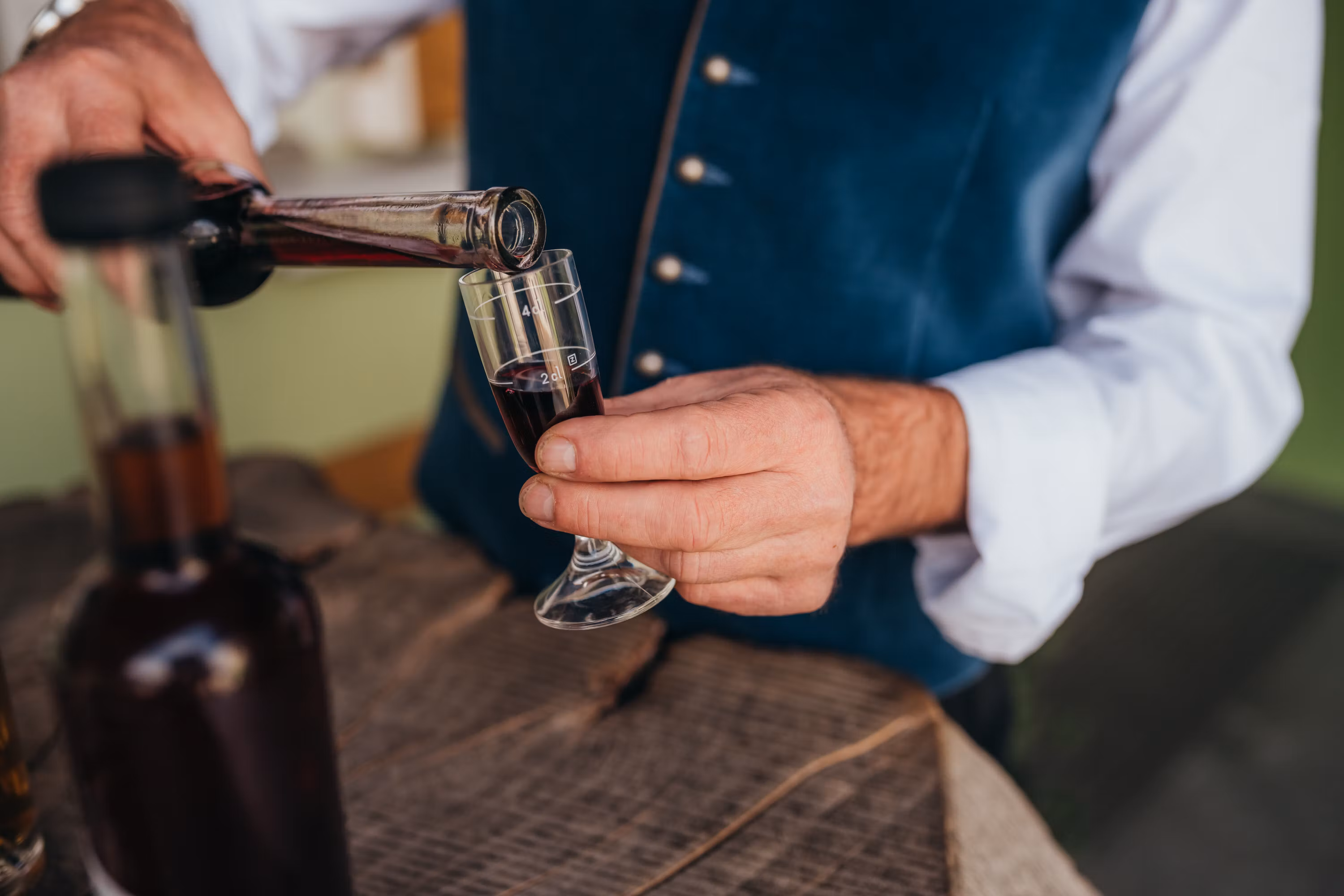 A személy vörös likőrt tölt egy kis pohárba.