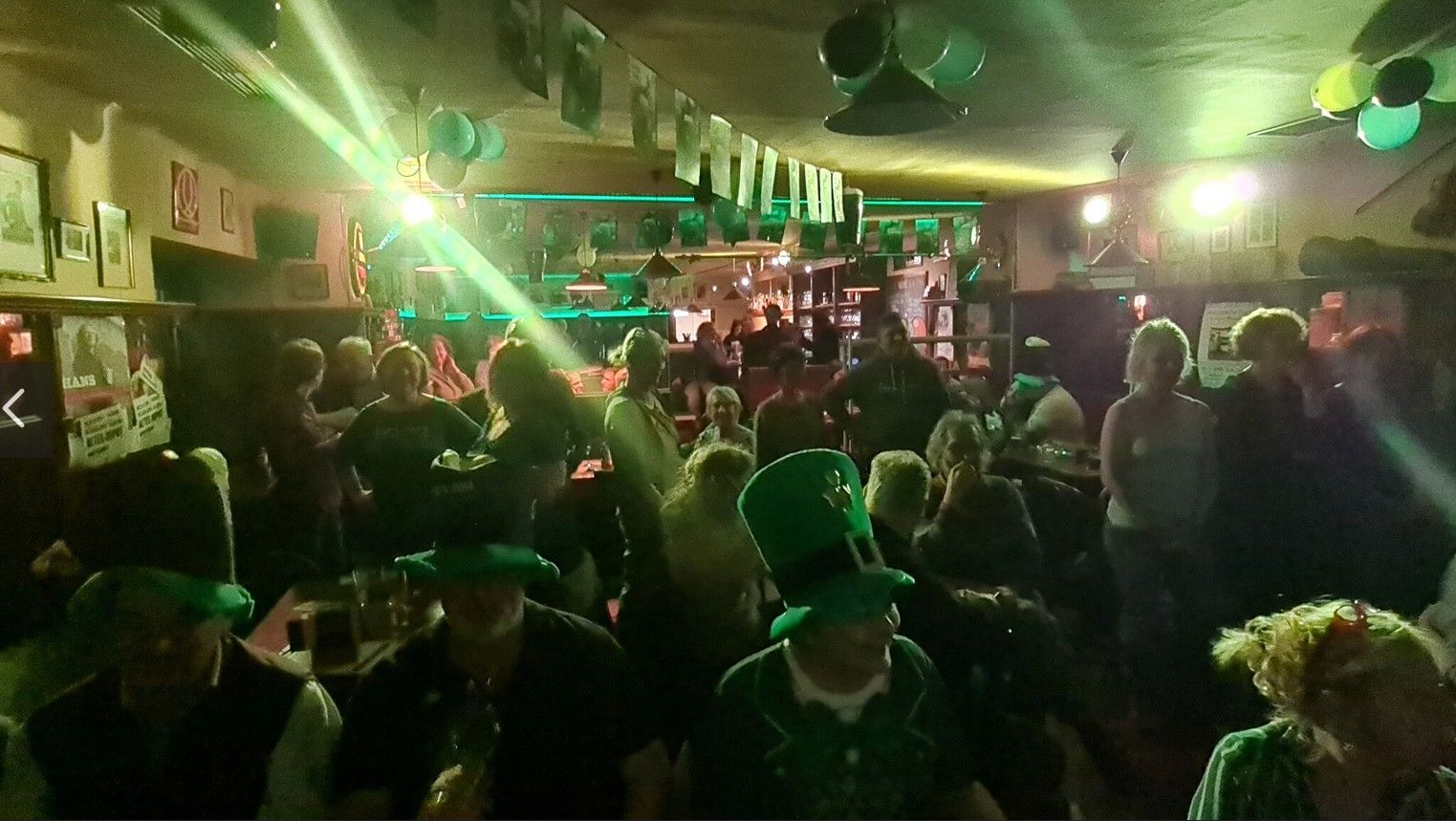 Az emberek egy kocsmában ünnepelnek zöld dekorációval és kalapokkal a Szent Patrik-napon.