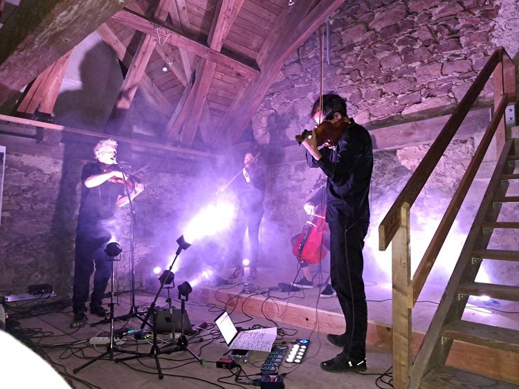 Zenészek játszanak egy rusztikus padláson, fényeffektekkel.