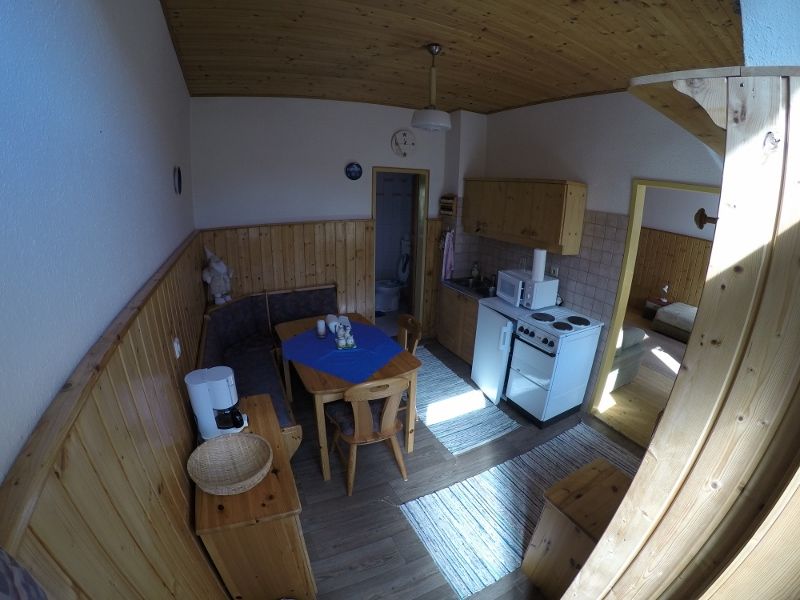 Konyha-nappali egy nyaraló apartmanban, fabútorokkal, étkezőasztallal, konyhasarokkal és hozzáféréssel egy hálószobához.