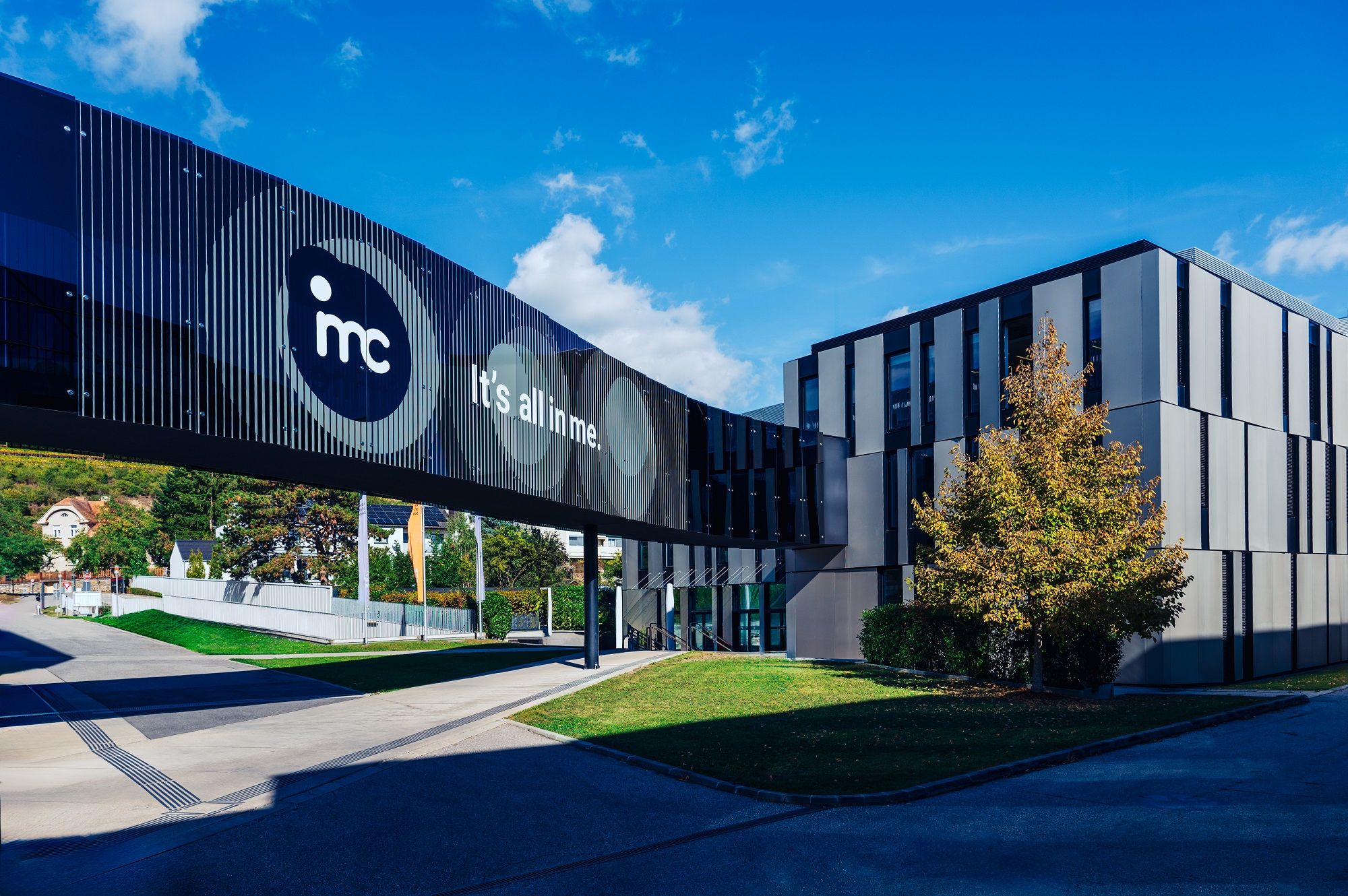 Az IMC Krems modern épülete üveghíddal és "It's all in me" felirattal.