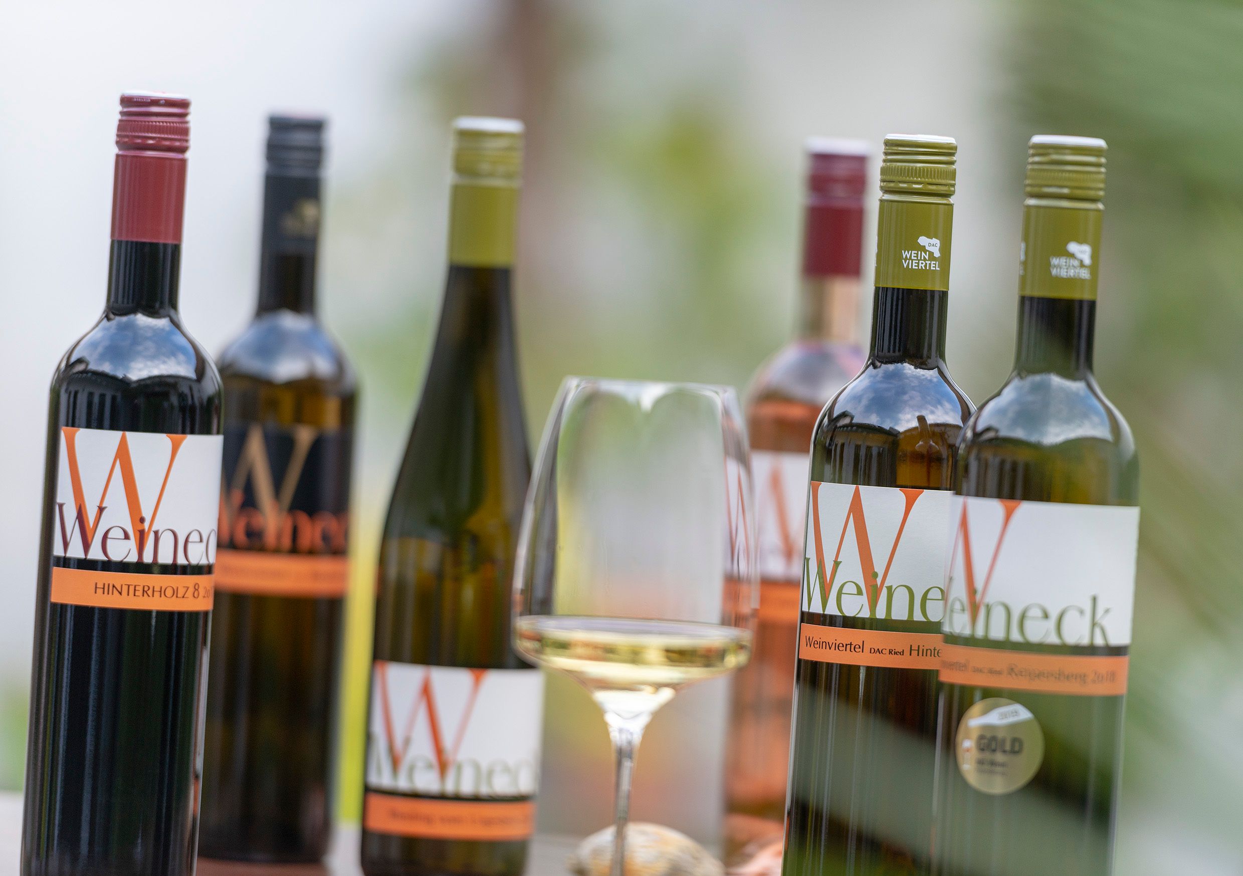 Különböző üvegek és egy pohár fehérbor az asztalon.