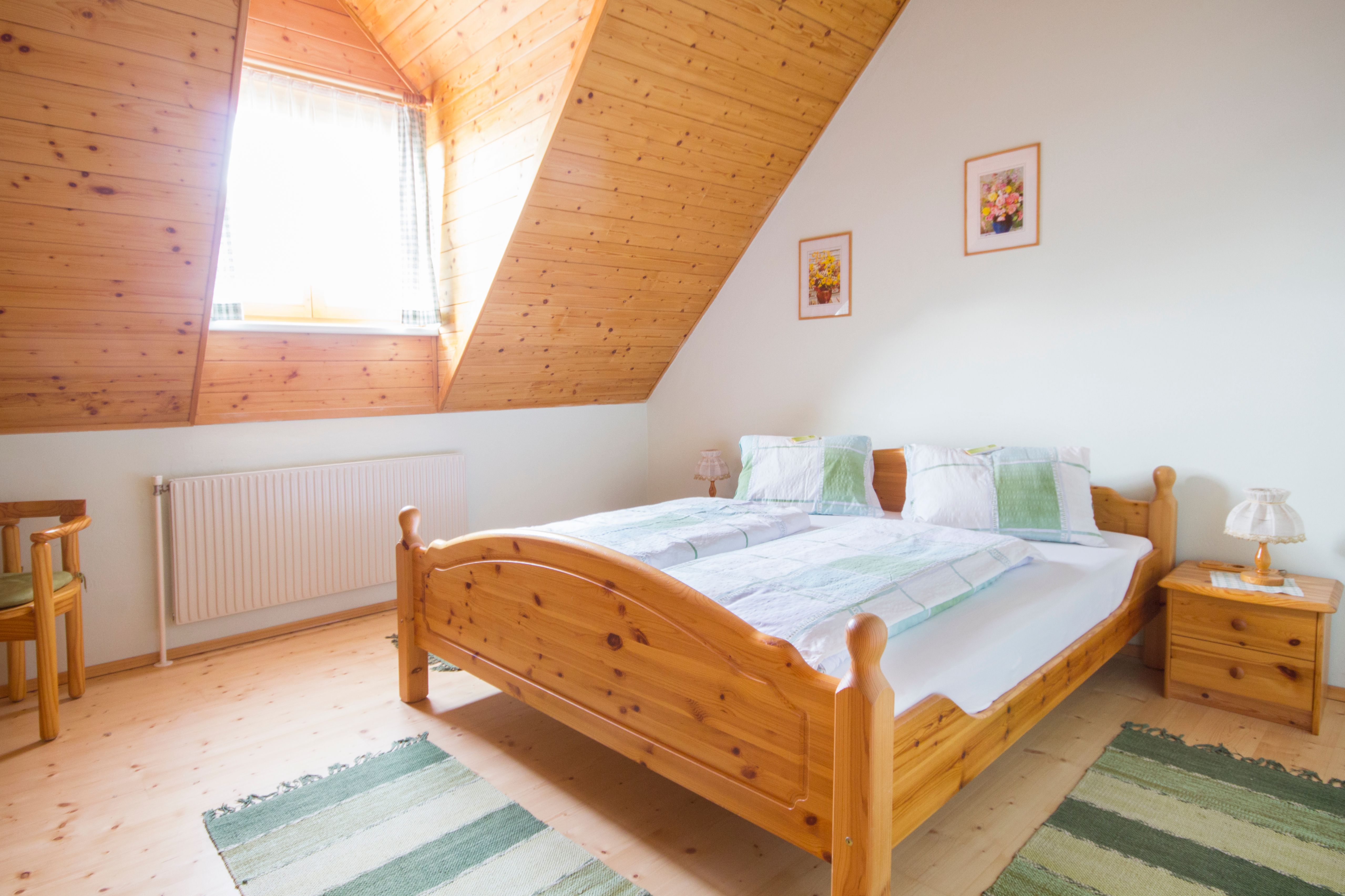 Hangulatos hálószoba fabútorokkal és ferde mennyezettel.