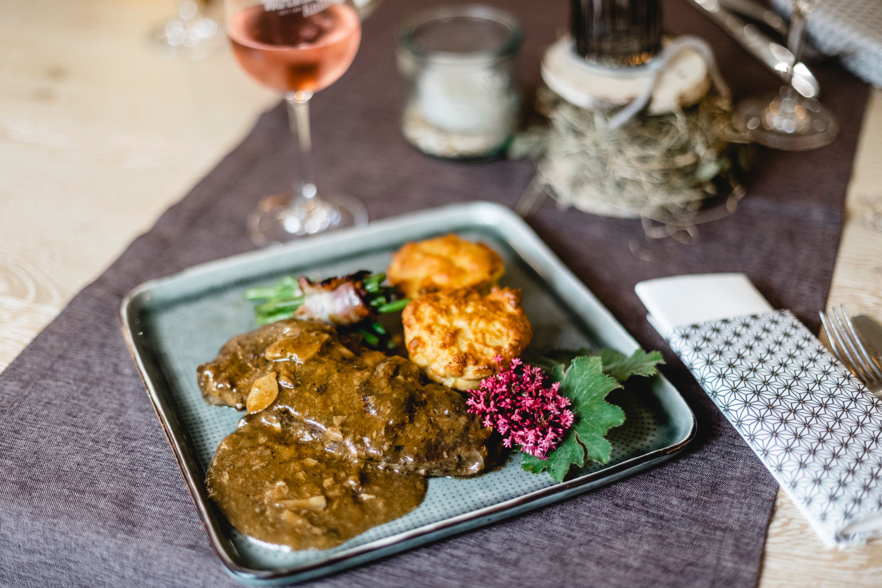 Egy tányér porcsinigombával töltött marhasült, köretekkel és virággal díszítve.