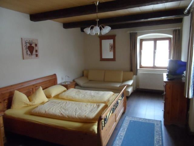 Hangulatos kétágyas szoba faággyal, kanapéval és ablakkal.