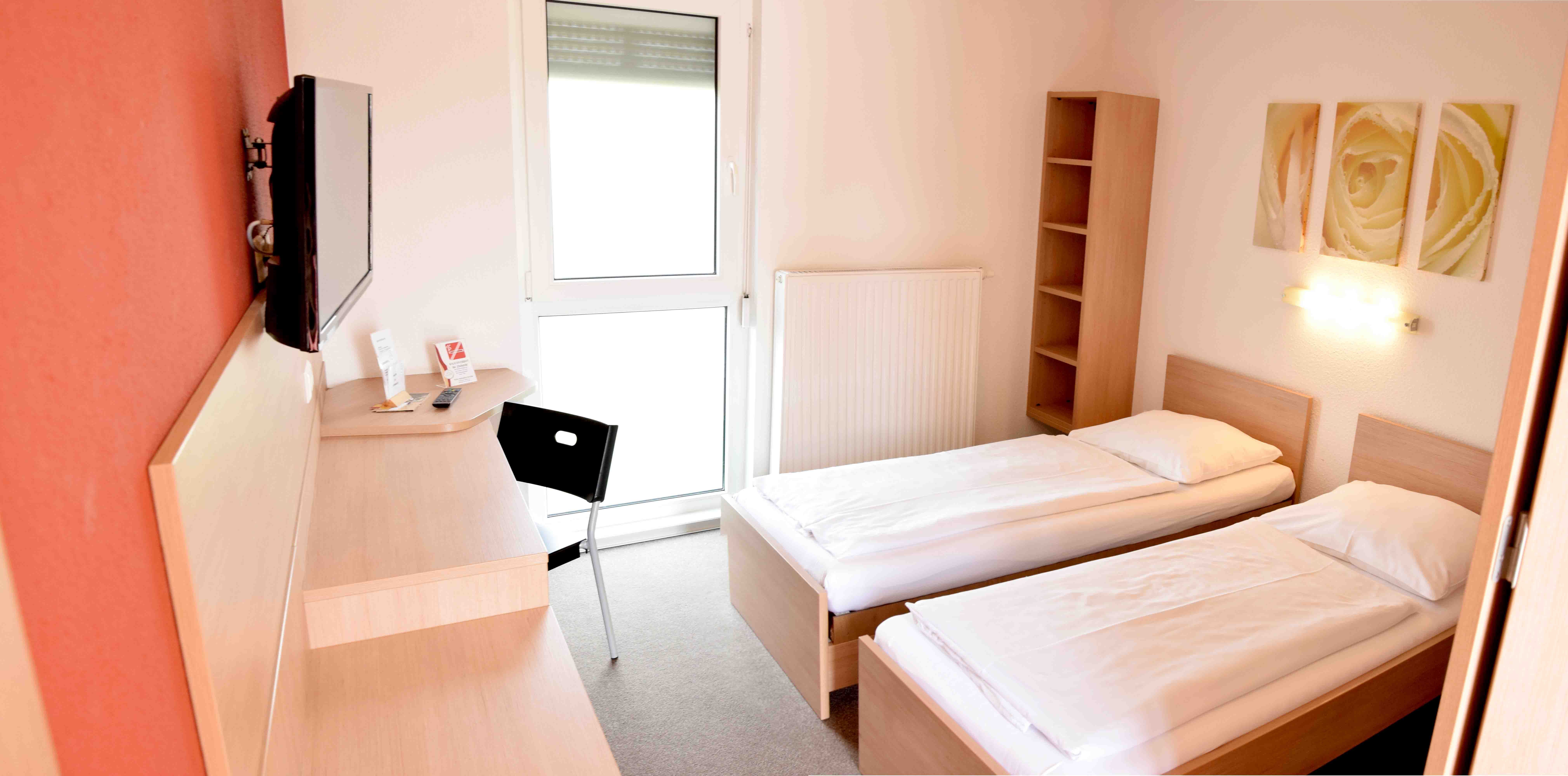 Egy egyszerű motelszoba két egyszemélyes ággyal, egy íróasztallal, egy székkel és egy TV-vel a falon.