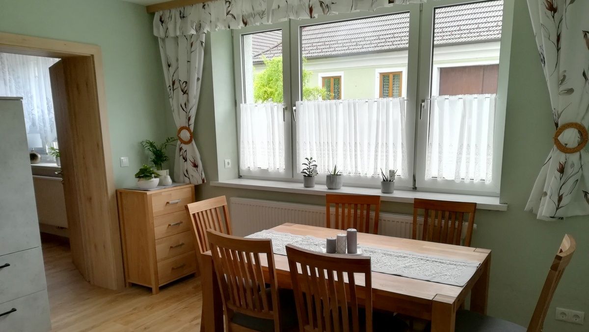Étkező, fa asztallal, székekkel és növényekkel az ablakpárkányon.